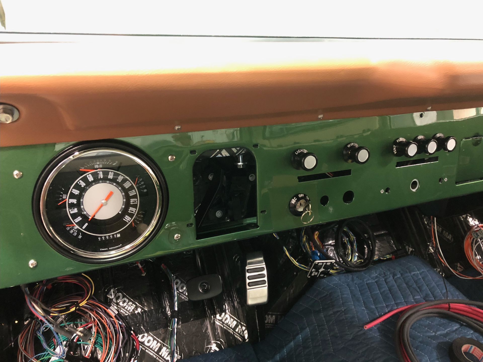 Classic car dashboard with green panel, round gauge, and exposed wiring under the dash