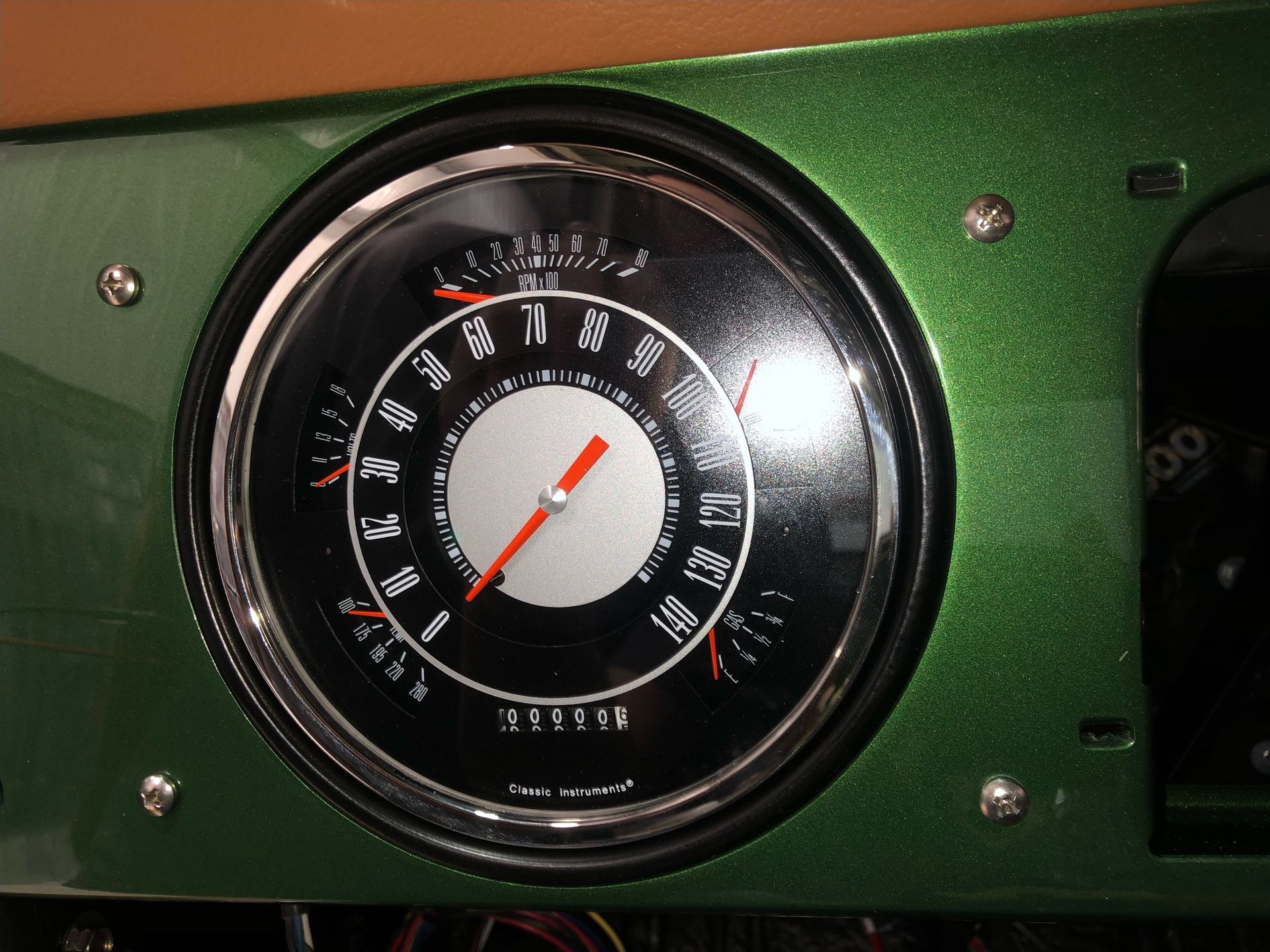 Close-up of a black vintage dashboard gauge with a red needle on a green panel.