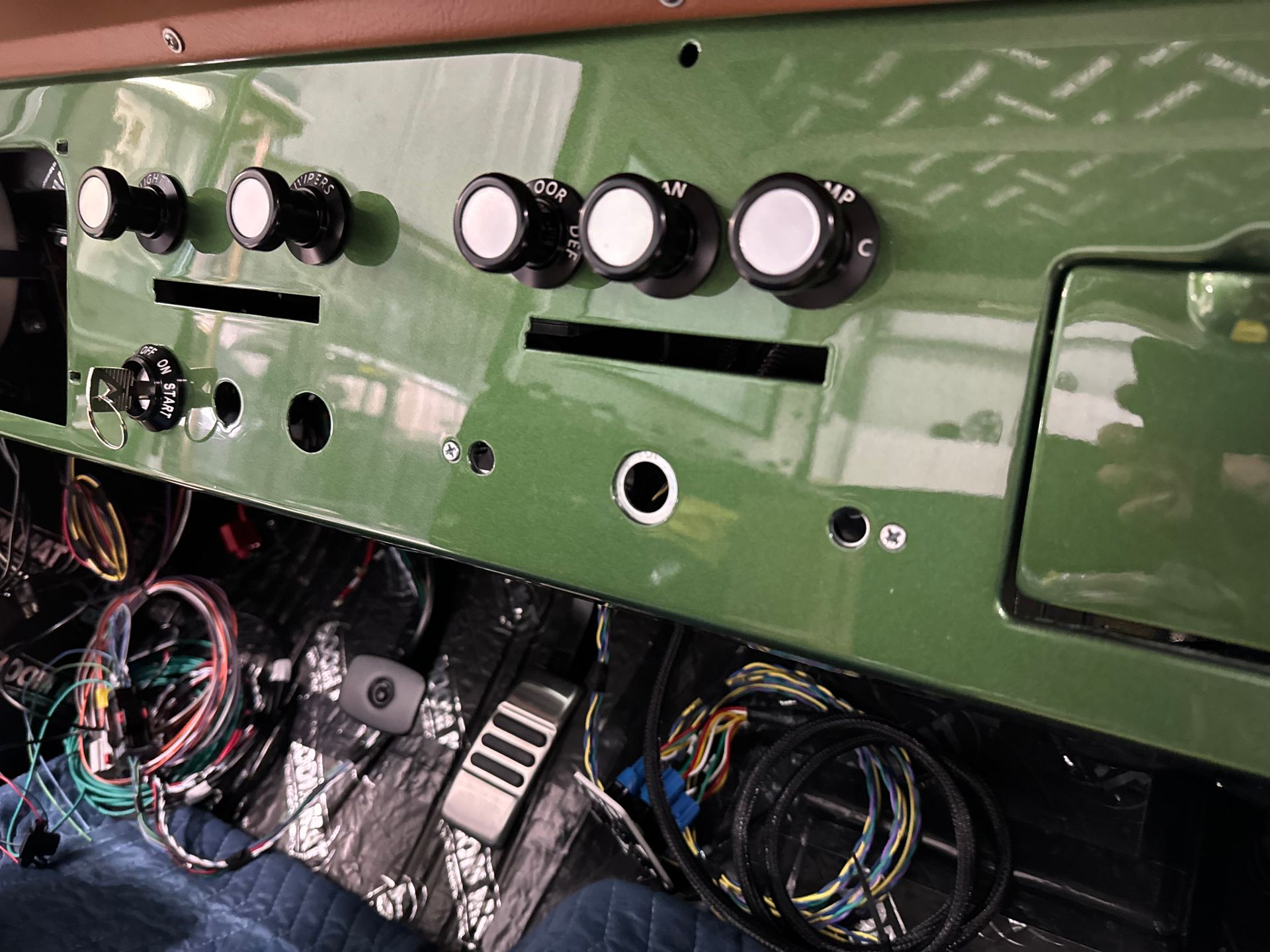Green vehicle dashboard with black knobs and exposed wiring beneath the panel