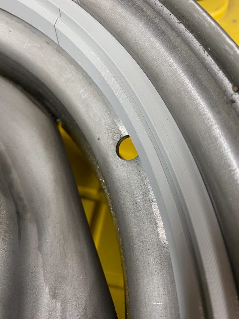Close-up of curved silver metal pipes with a yellow background visible through gaps