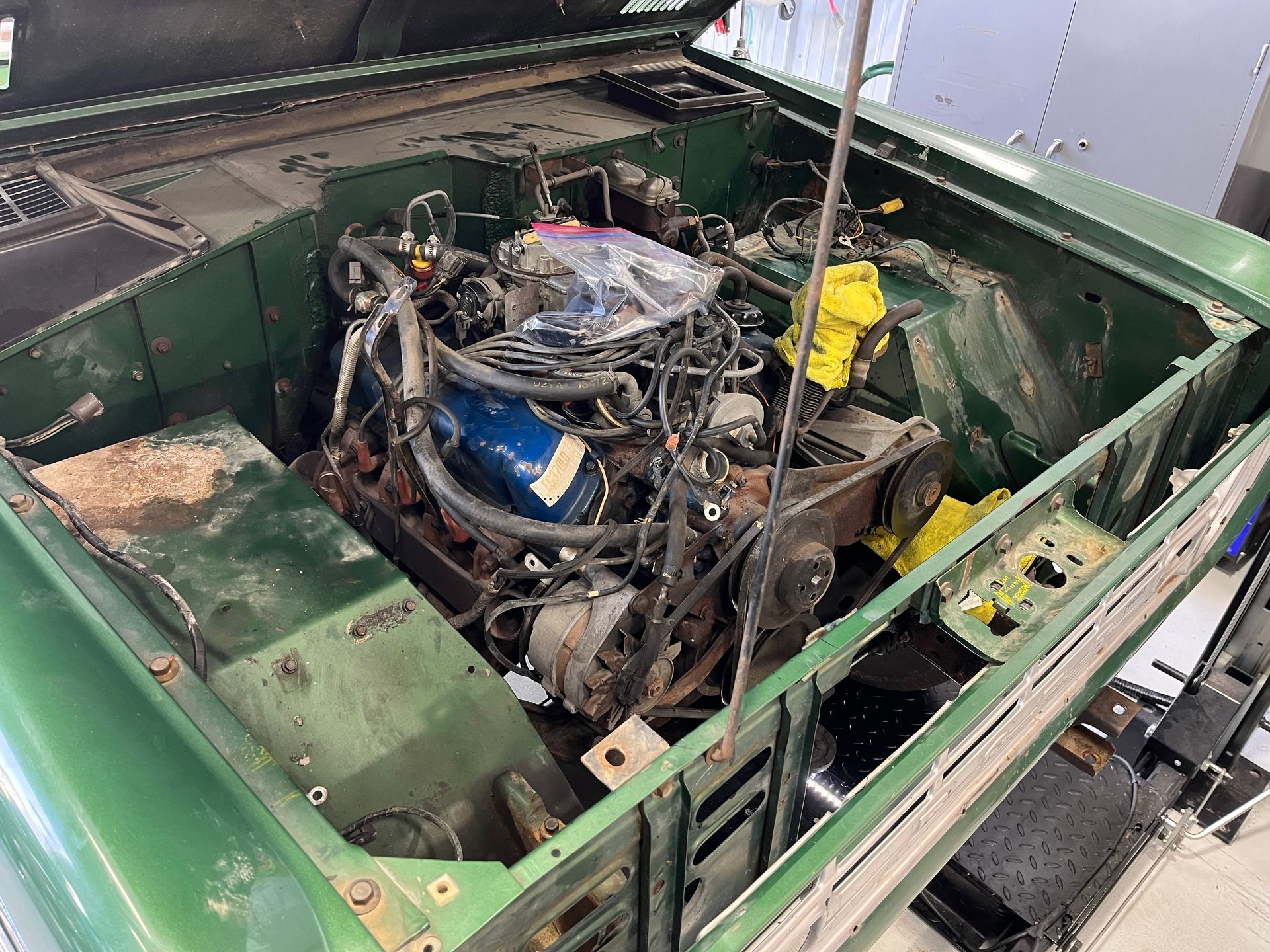 Green car body with a partially removed engine exposed in the engine bay.