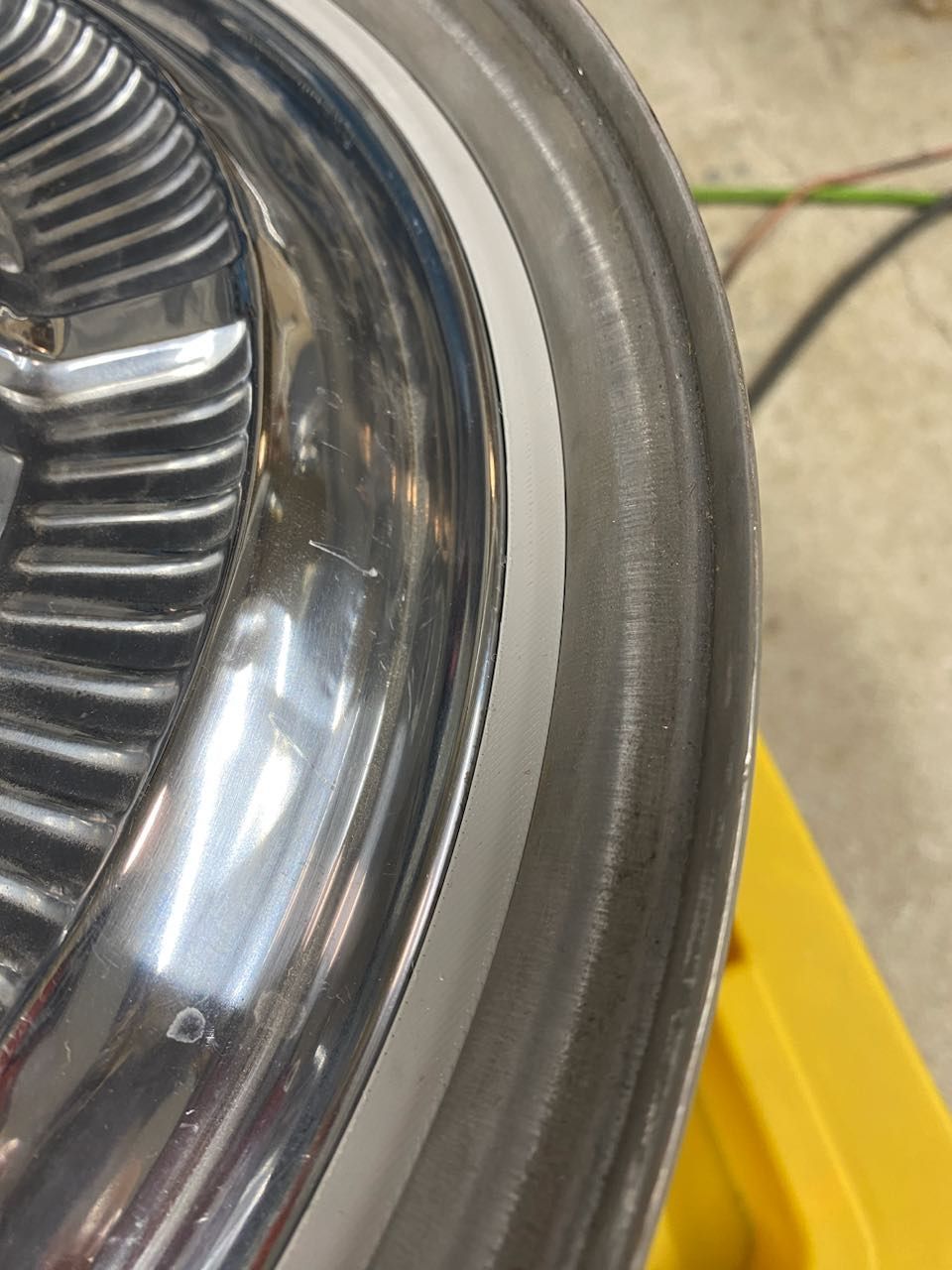 Close-up of a chrome car headlight with a rubber trim edge and yellow panel nearby