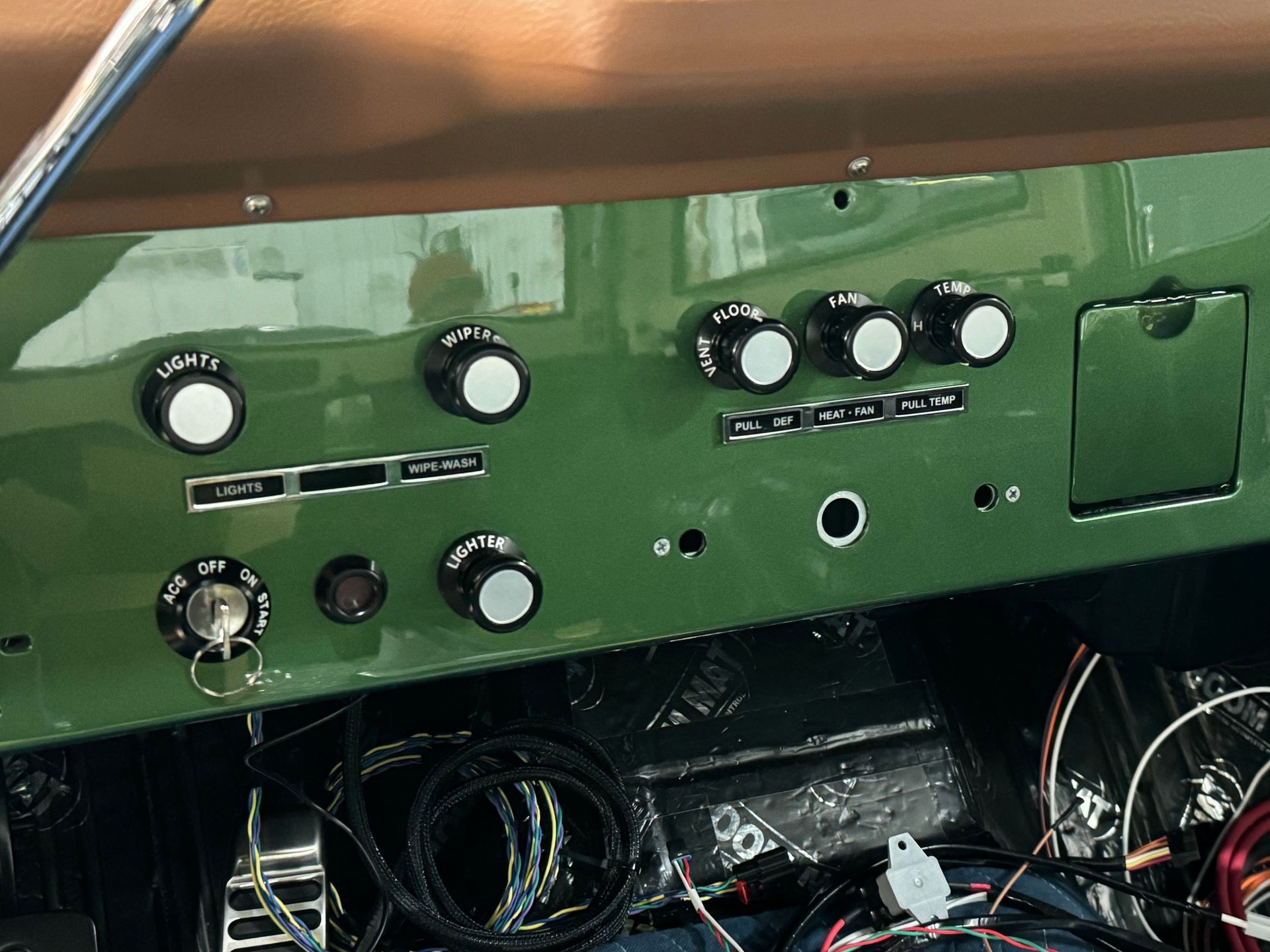 Green control panel with black knobs and switches above a compartment of tangled cables