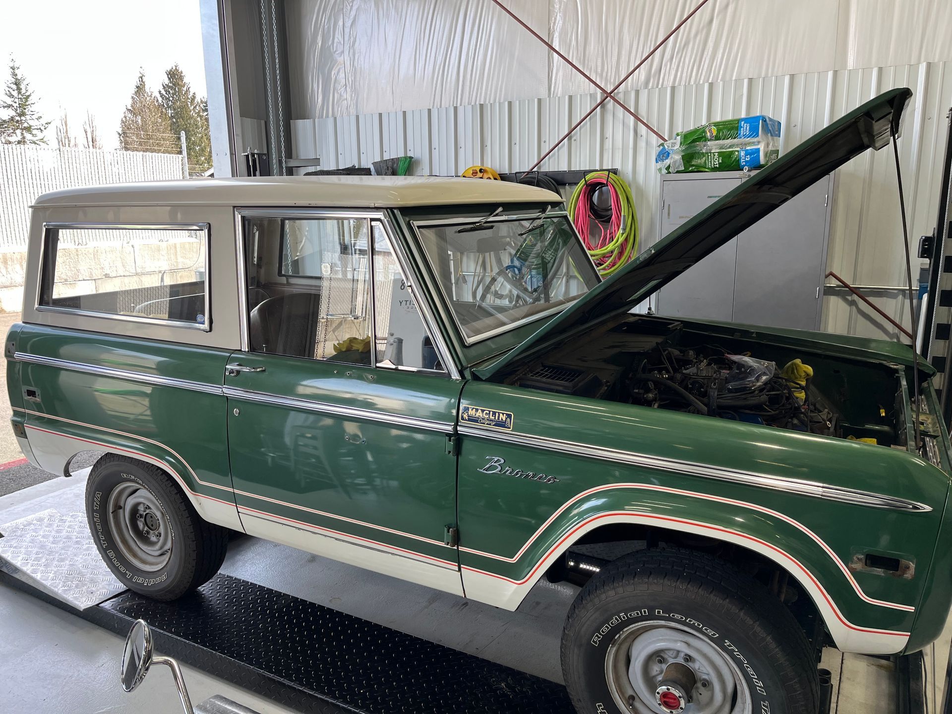 Green vintage SUV with hood open in a garage or workshop