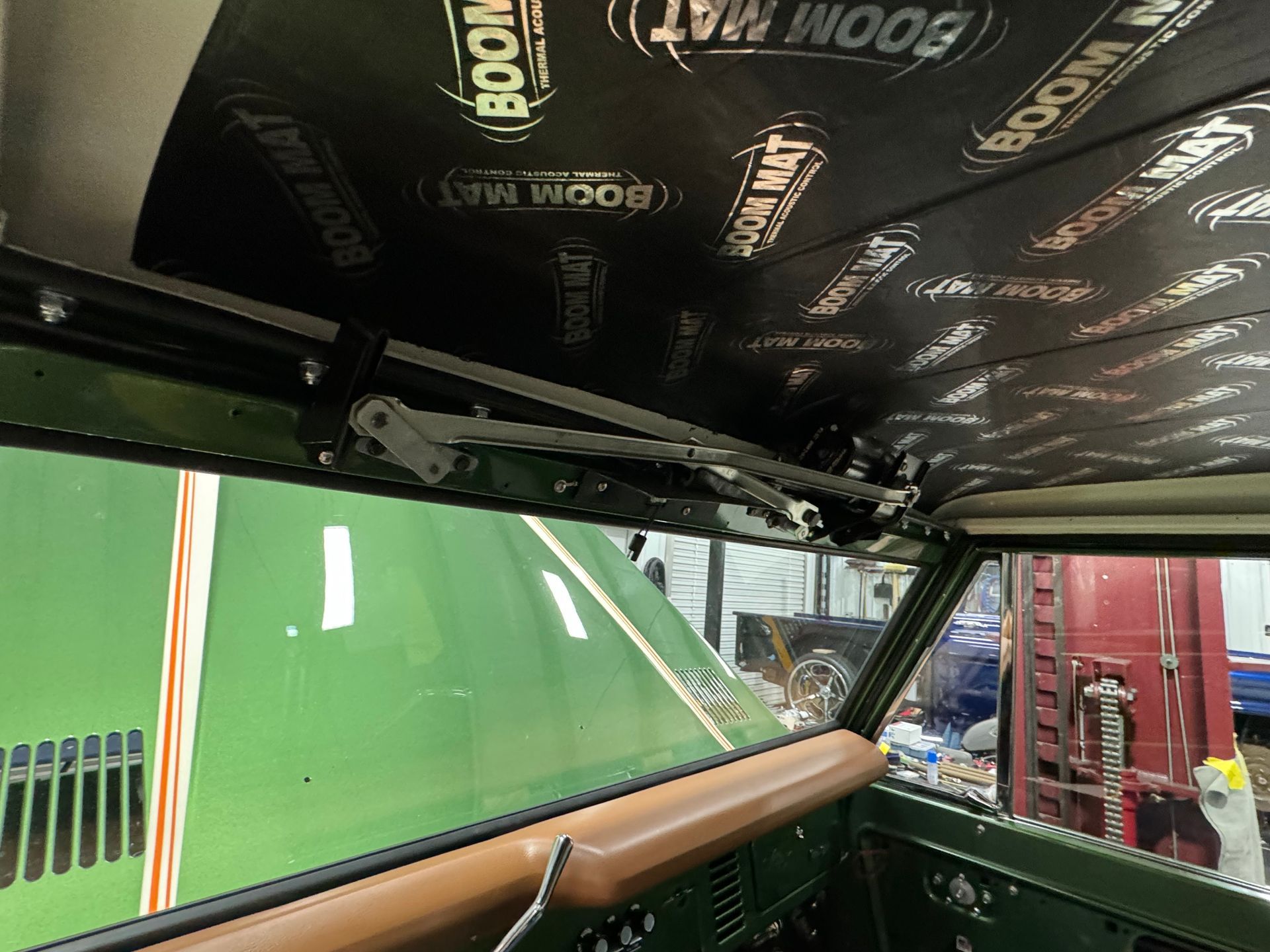 Inside a vehicle, a black “Momo” headliner and green hood are visible through the windshield.