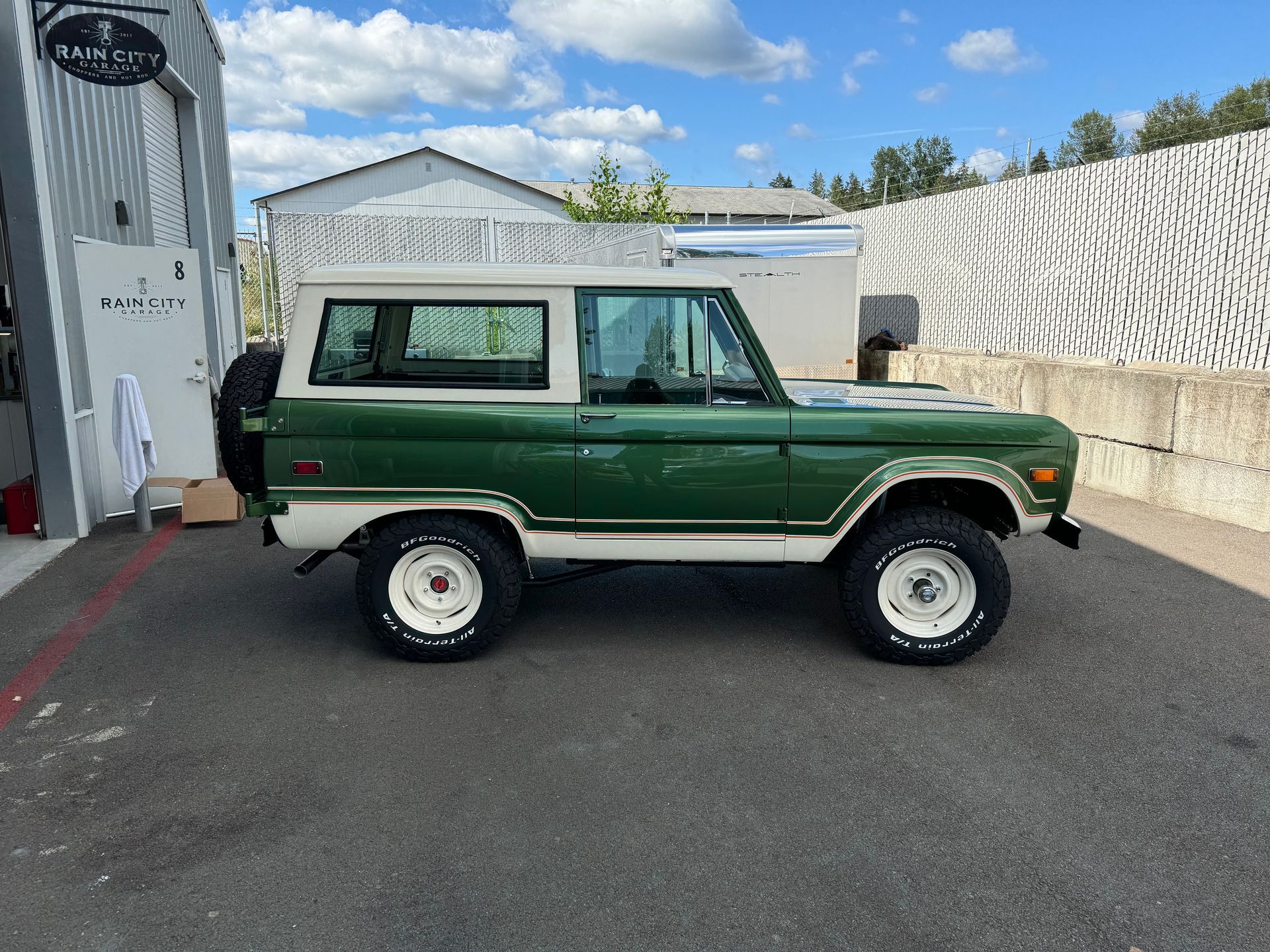Green-and-white vintage SUV parked outside a building on a sunny day