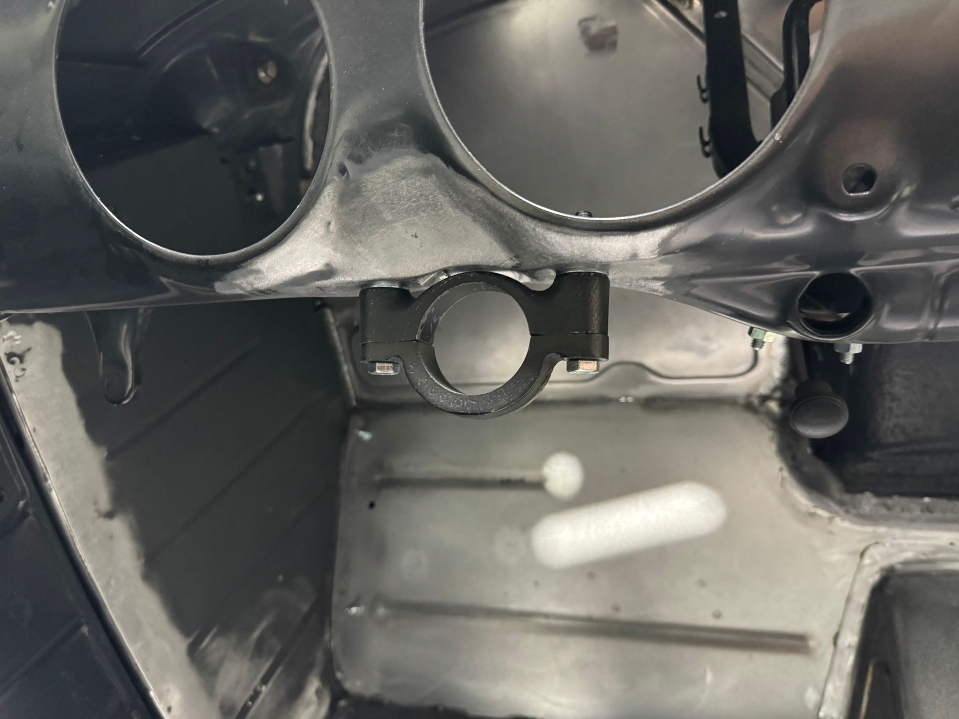 Interior of a car dashboard with exposed metal and circular gauge openings, likely under repair