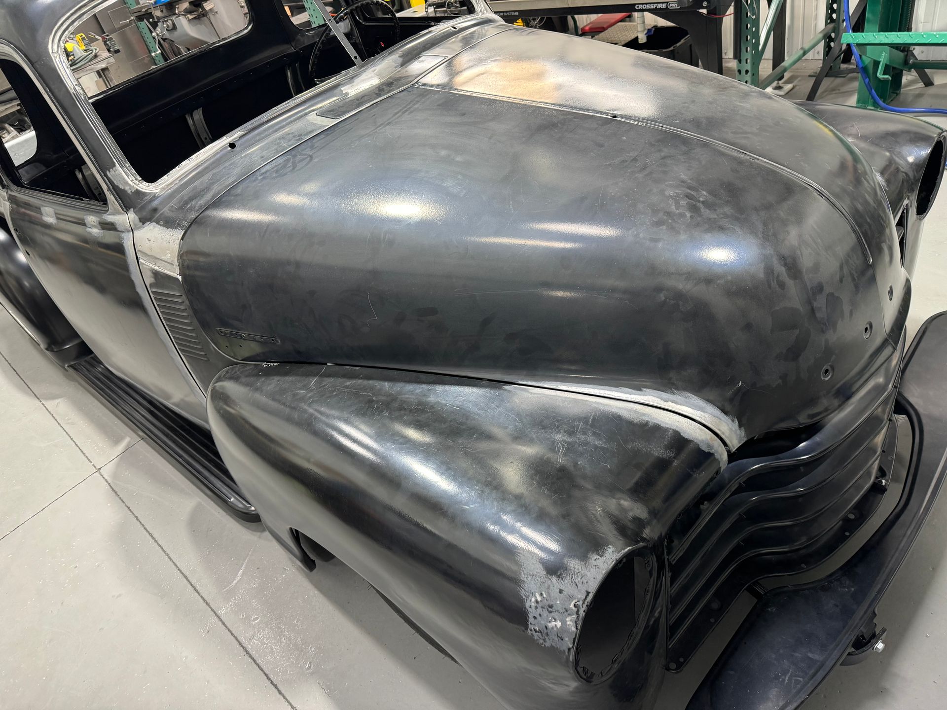 Custom black car body in a garage, showing the hood and front grille