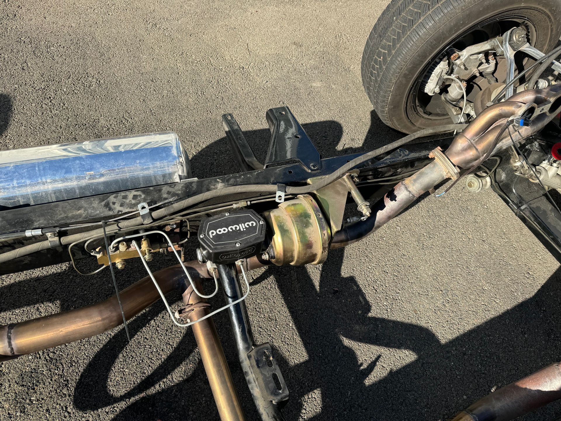 Close-up of a bicycle’s handlebar and front wheel on pavement, showing wiring and a mounted blue tube.
