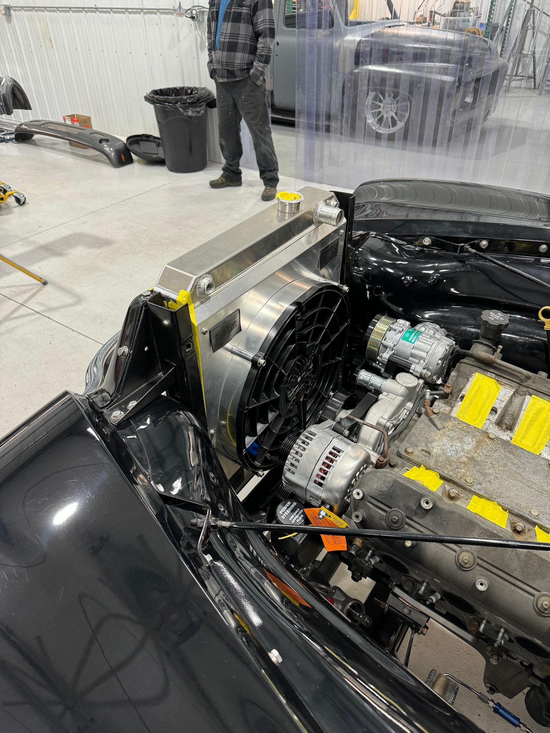 Sports car engine bay with exposed engine and yellow safety markers in a garage
