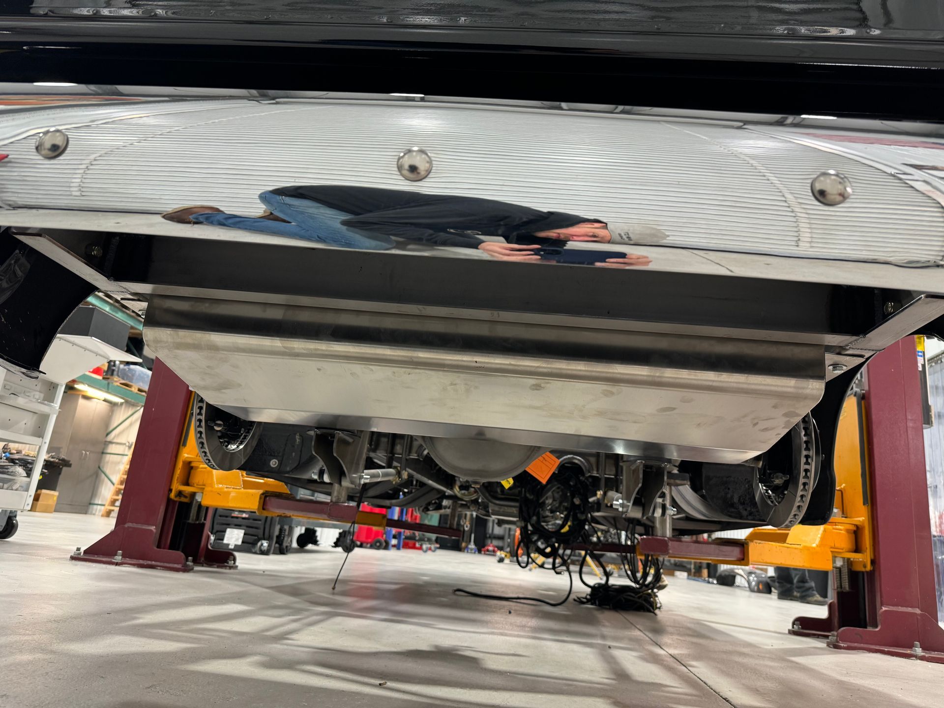 Car undercarriage on a lift in an auto repair shop, with tools and equipment visible underneath