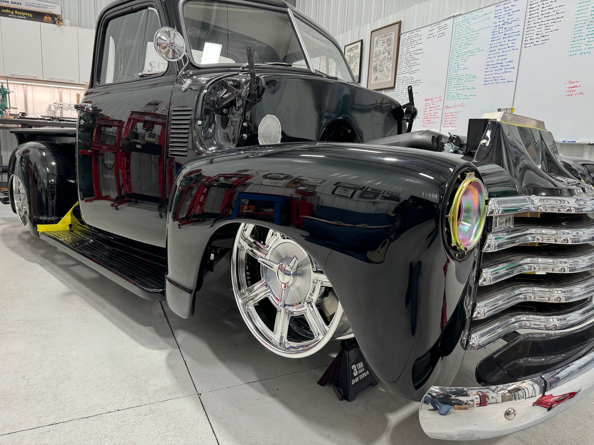 Black custom vintage pickup truck with chrome grille and wheels in a showroom
