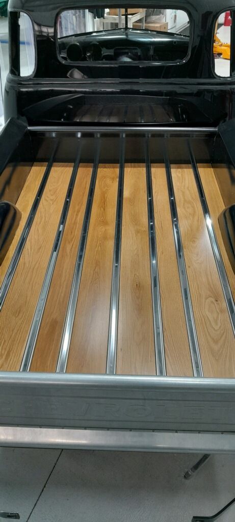 Wooden slatted cargo bed inside an open vehicle, viewed from the rear.