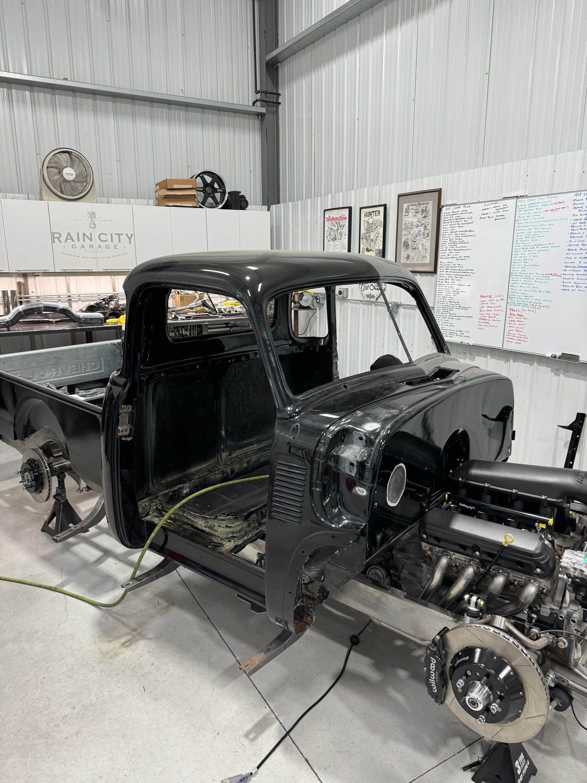 Partially restored vintage truck cab in a workshop, with exposed chassis and engine components.
