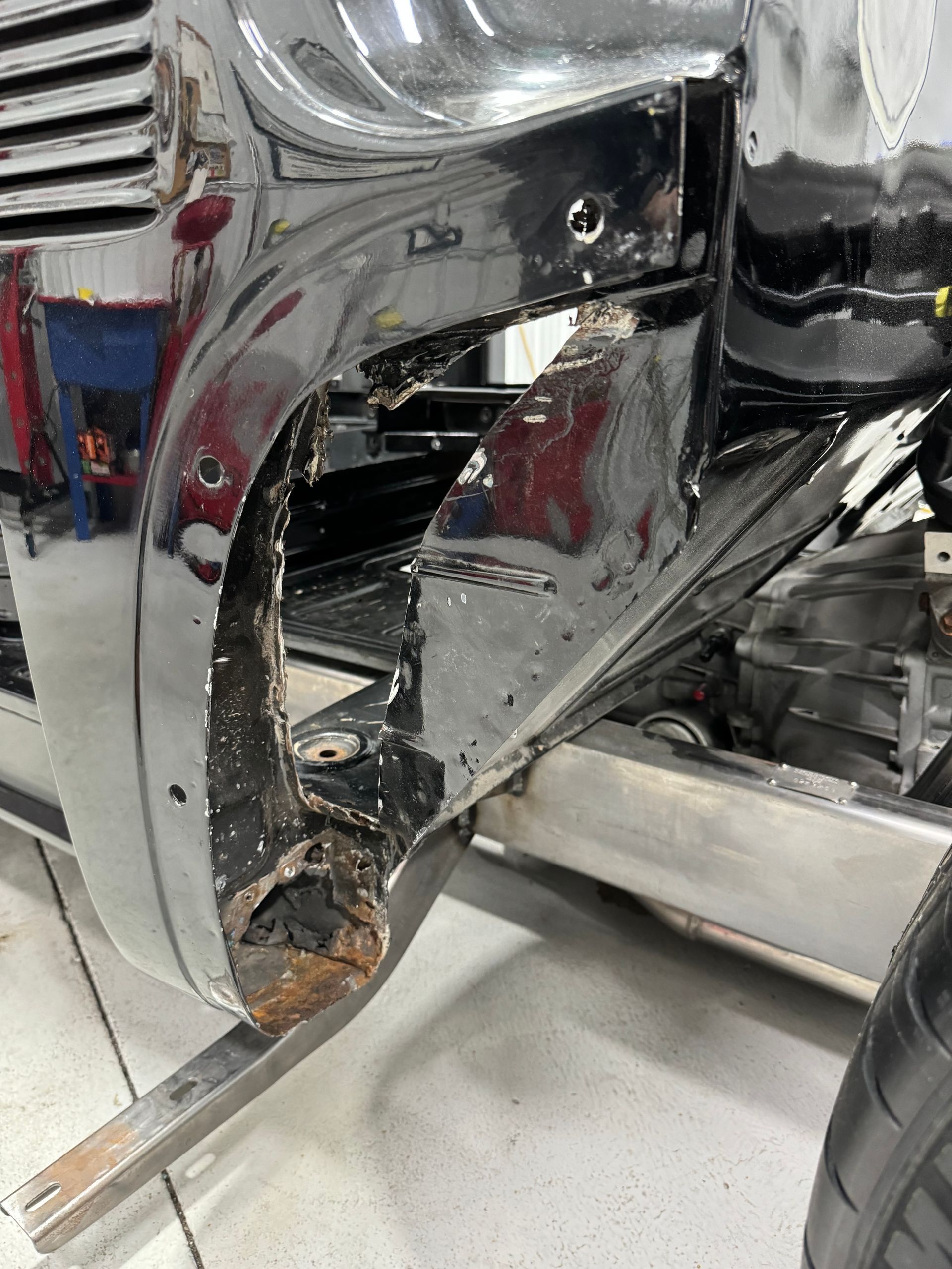 Damaged chrome vehicle body with a large torn opening near the rear wheel