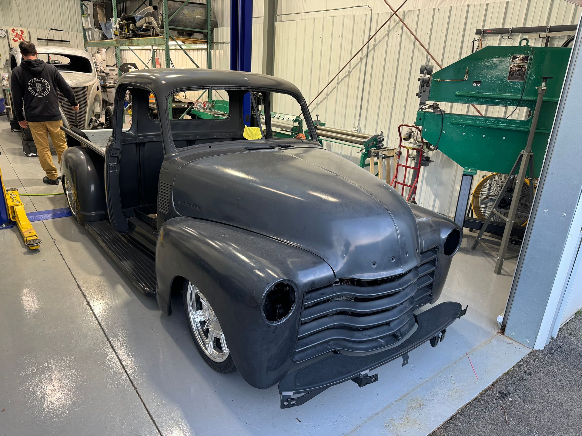 Matt black custom vintage pickup truck in a workshop, front view with bodywork in progress