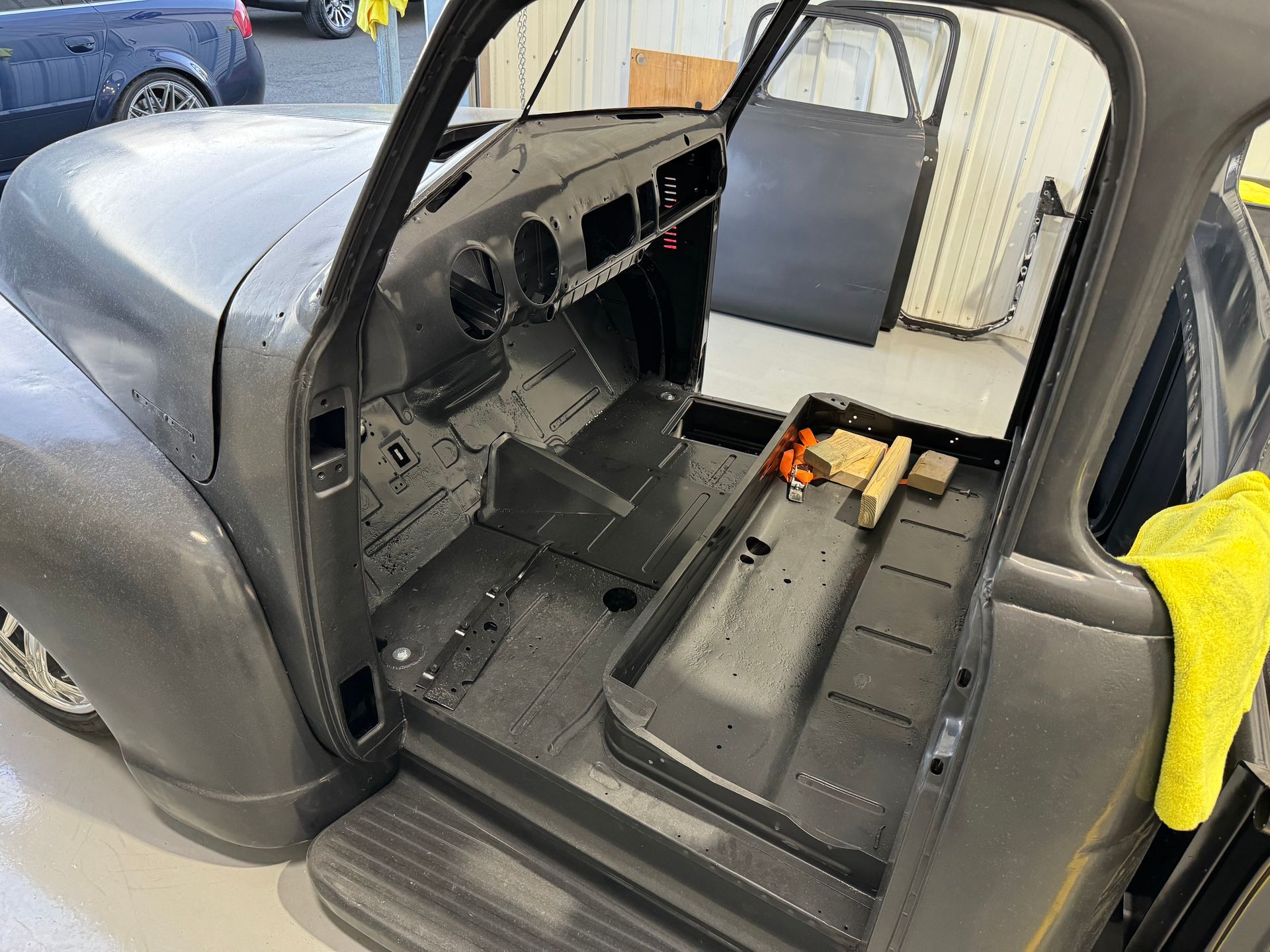 Empty gray car interior with exposed floor and dashboard during restoration