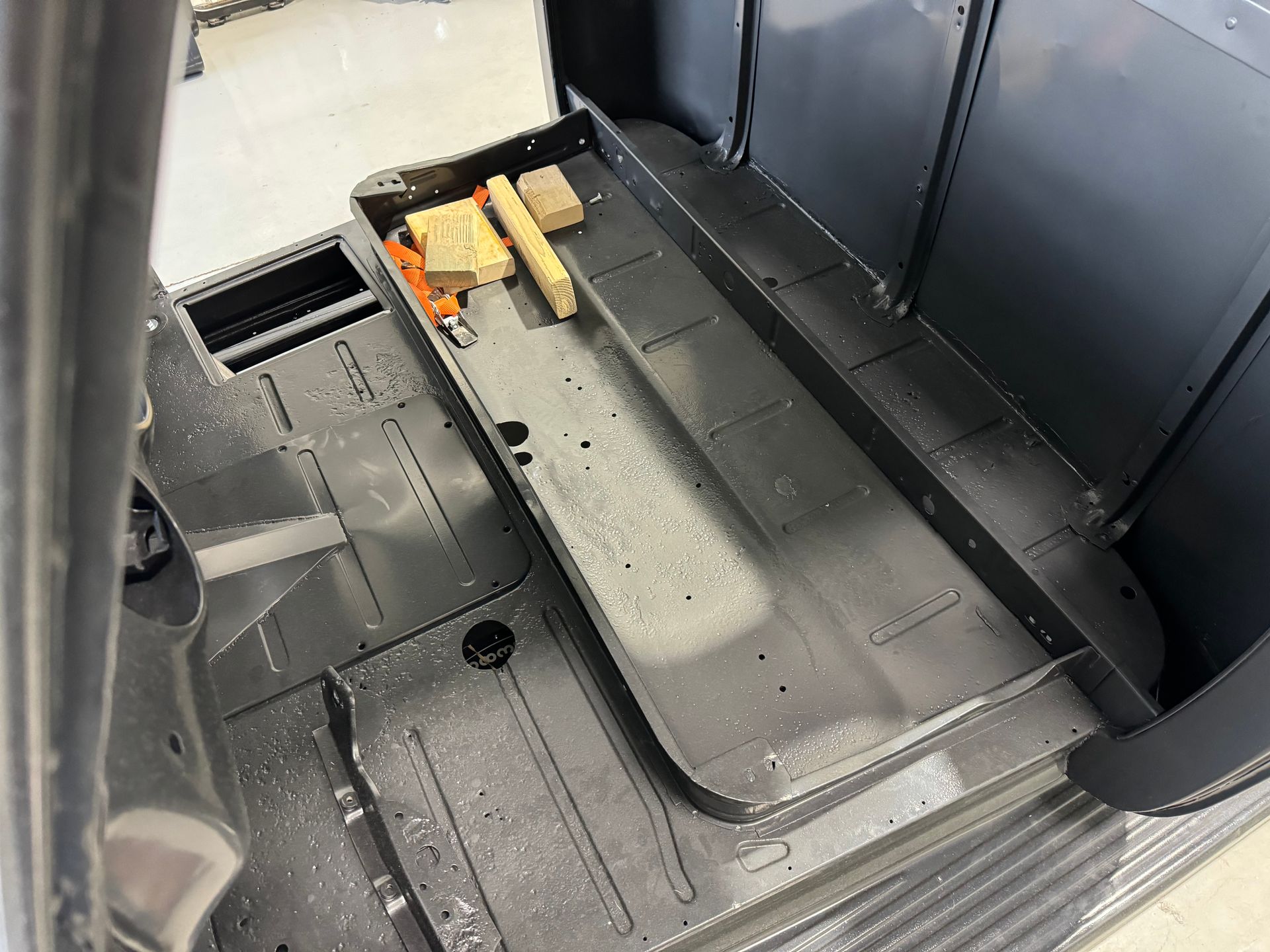 Empty black equipment compartment with a gray tray and a few wooden blocks inside