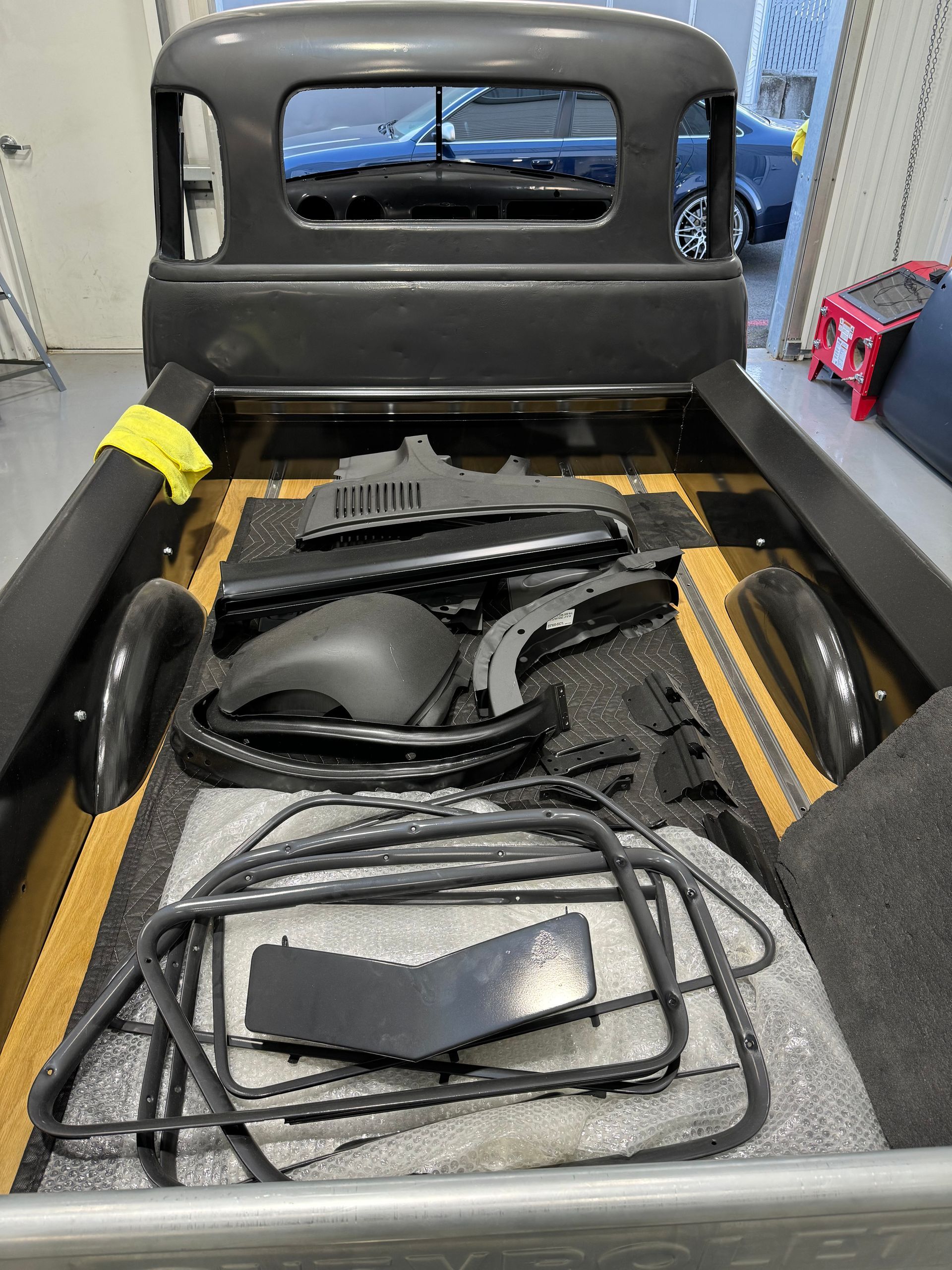 Black car cab interior with loose seat panels, wiring, and parts laid in the cargo area