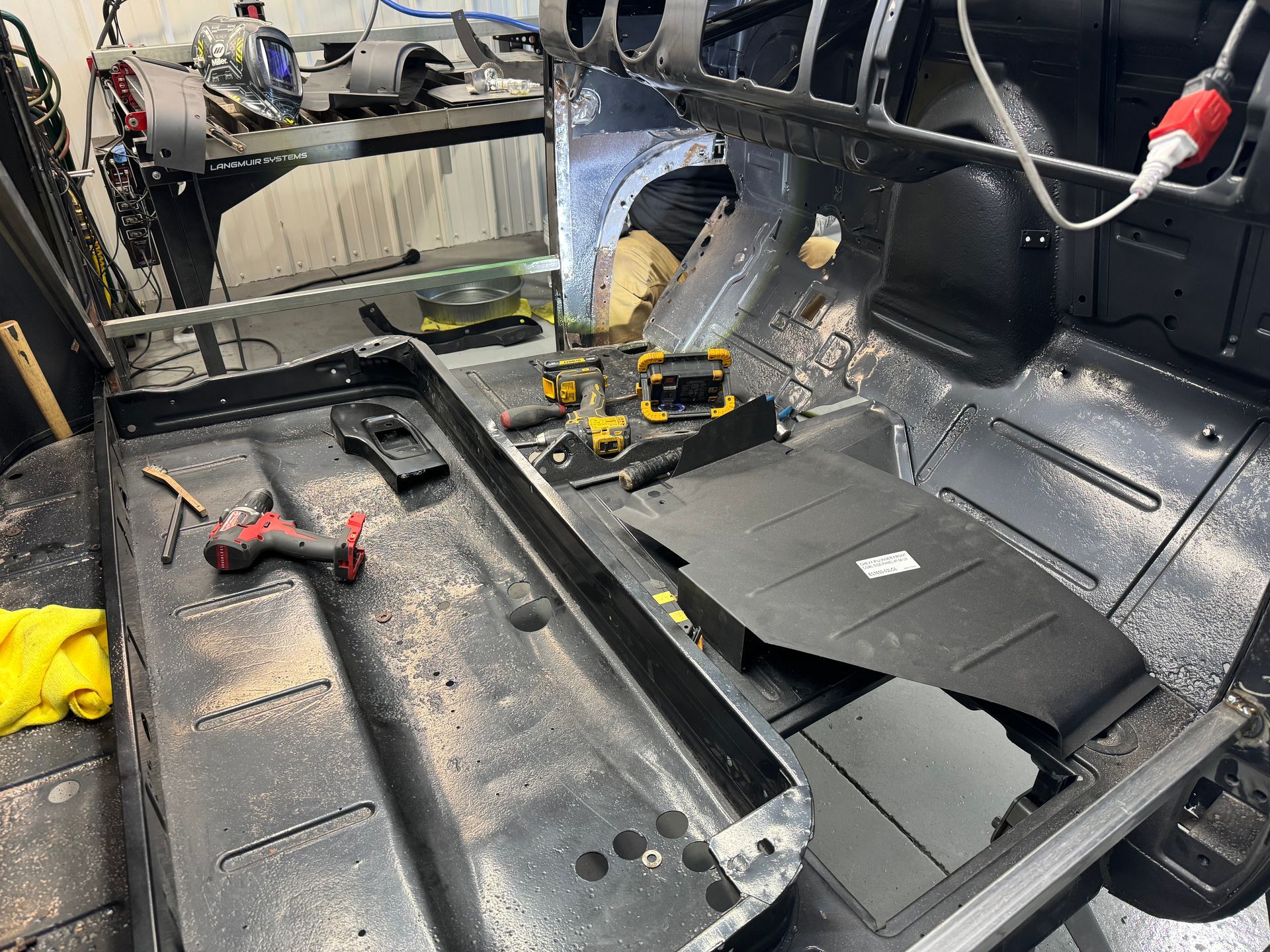 Car interior being repaired, with removed panels, tools, and exposed wiring on the floor