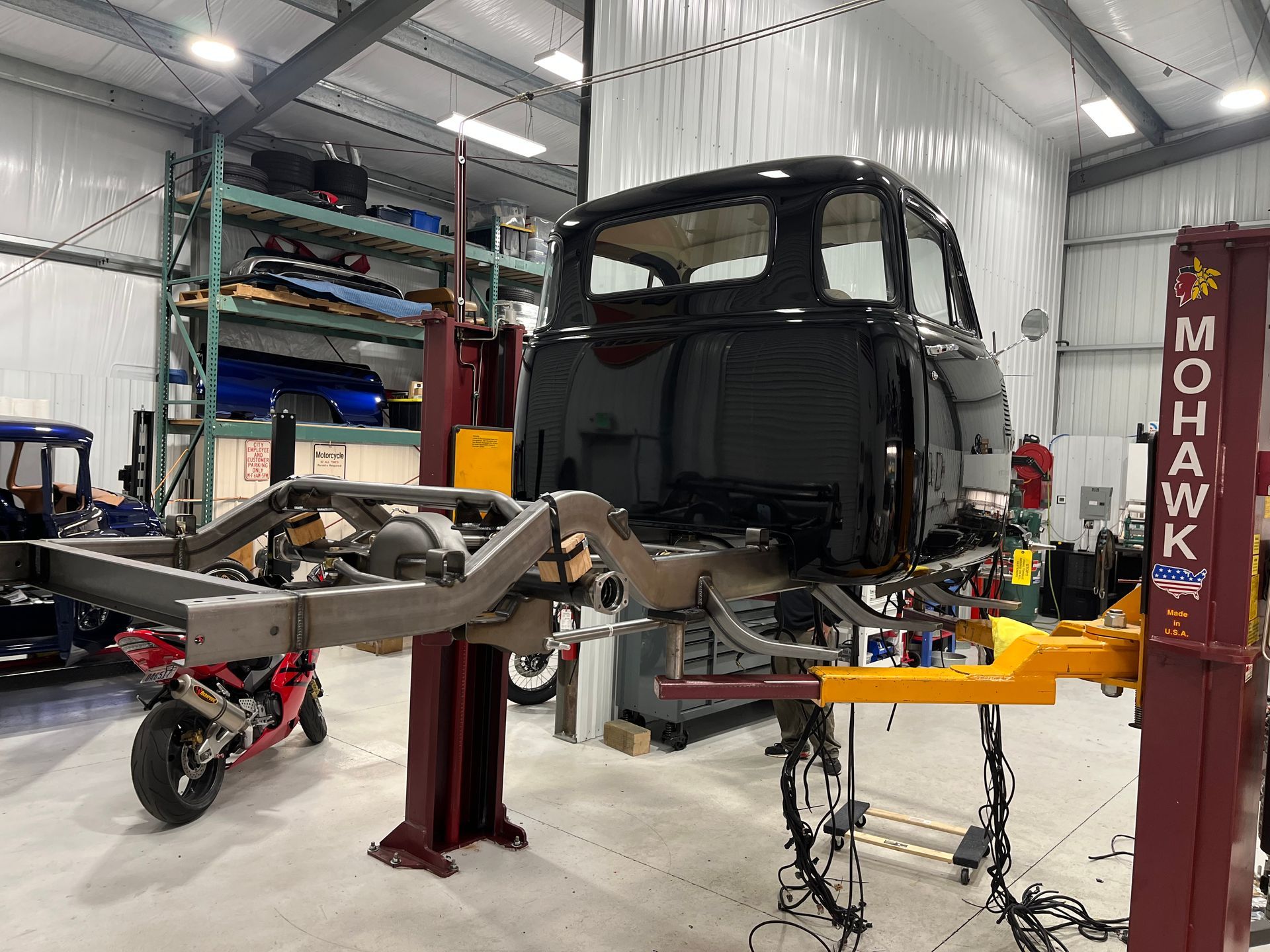 Car chassis on lift in auto shop, with exposed frame and tools around it