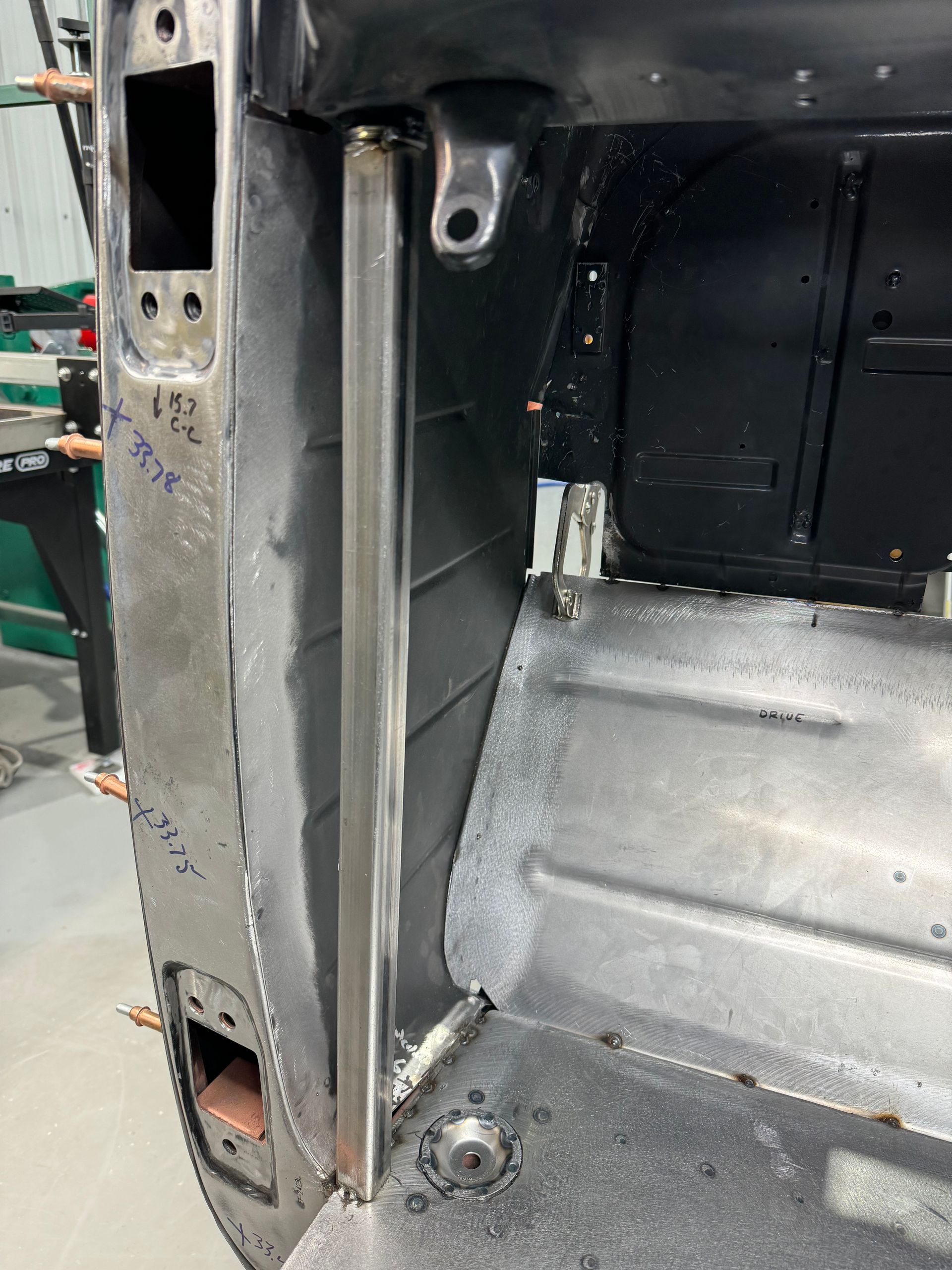 Close-up of a damaged car interior door frame and floor pan with exposed bare metal and rust.