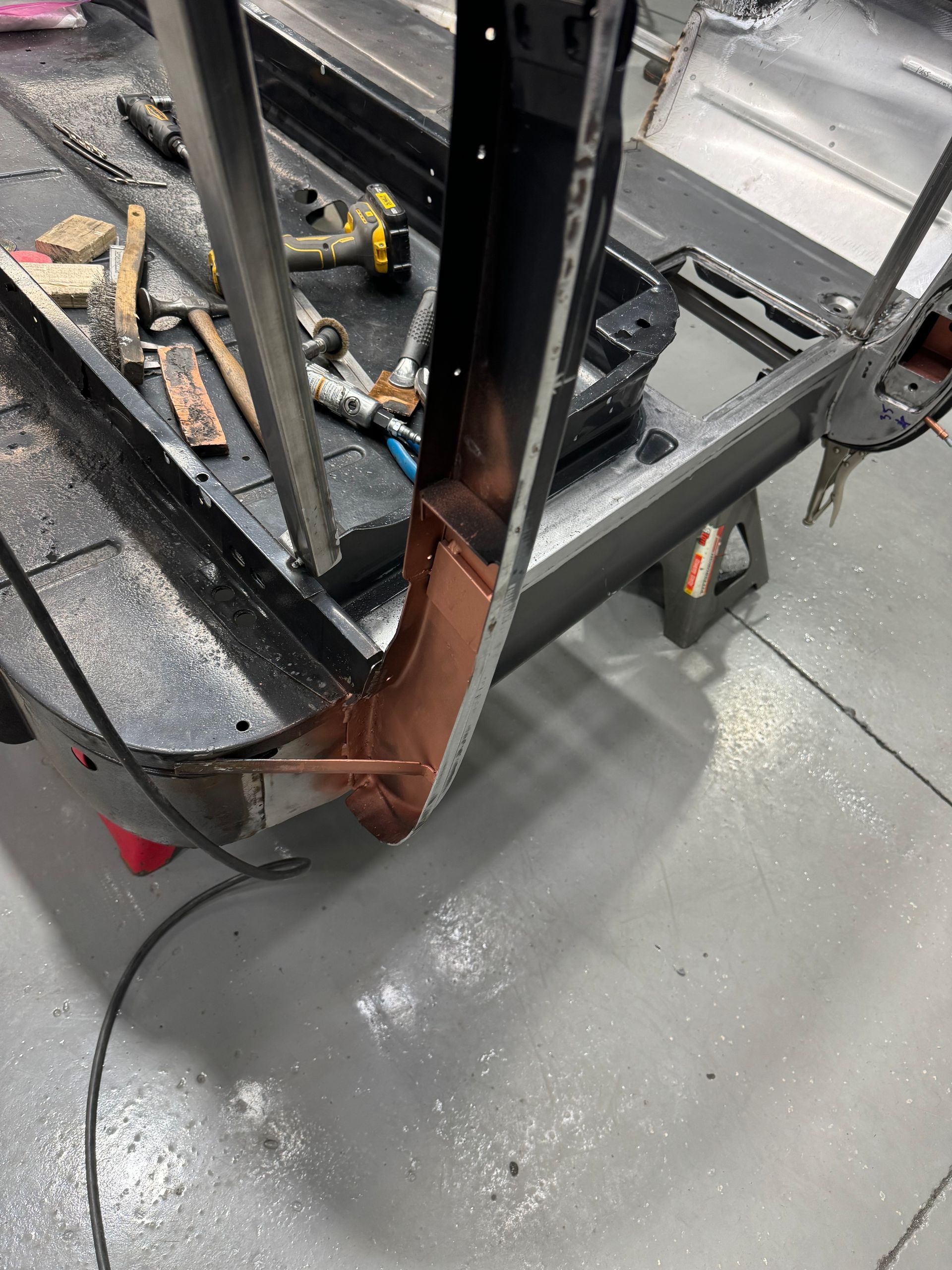 Worn metal railing with rust, leaning over a gray concrete floor in a workshop or garage.