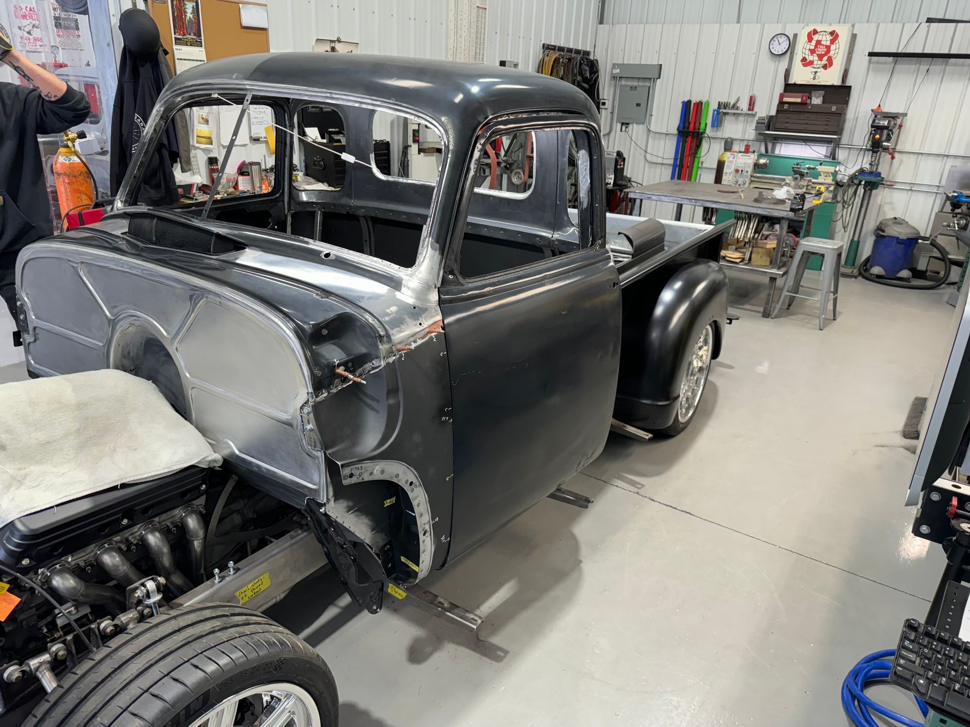Partially restored black vintage car in a workshop with exposed engine and tools nearby