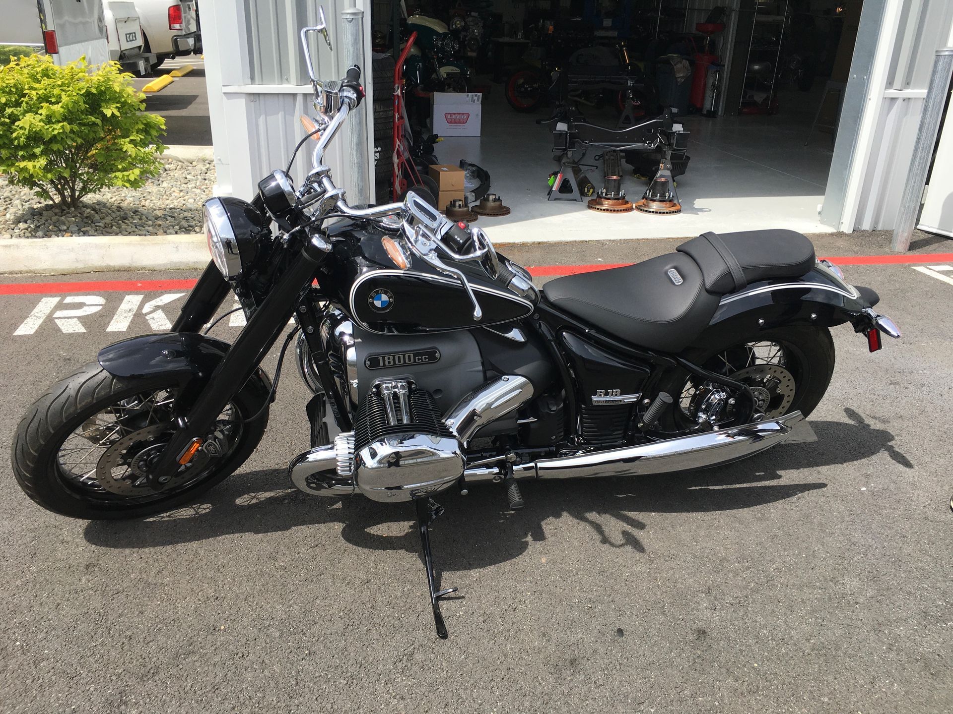 Black cruiser motorcycle parked outside a shop on a sunny street