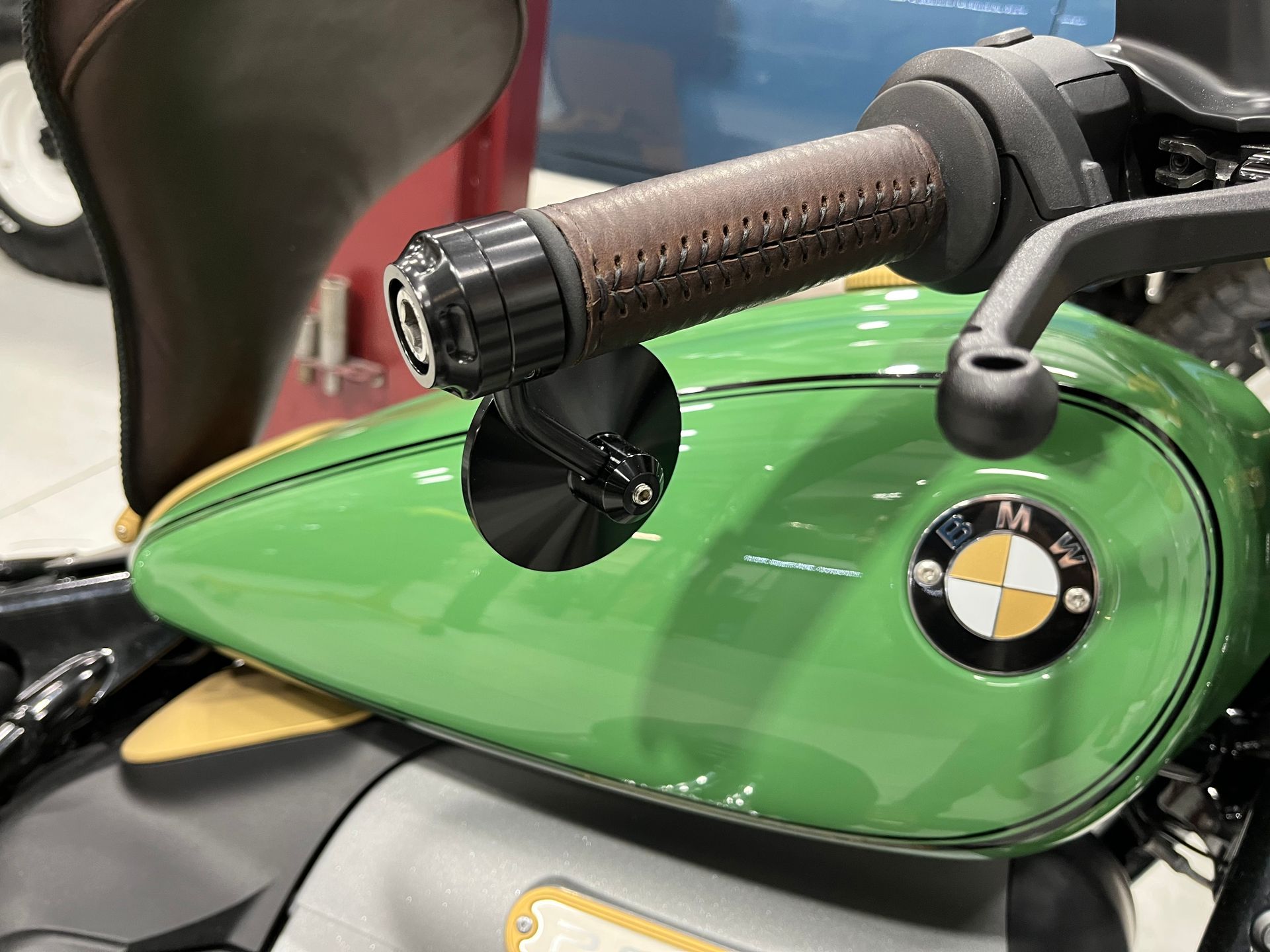 Close-up of a green motorcycle fuel tank and brown handlebar grip with BMW logo