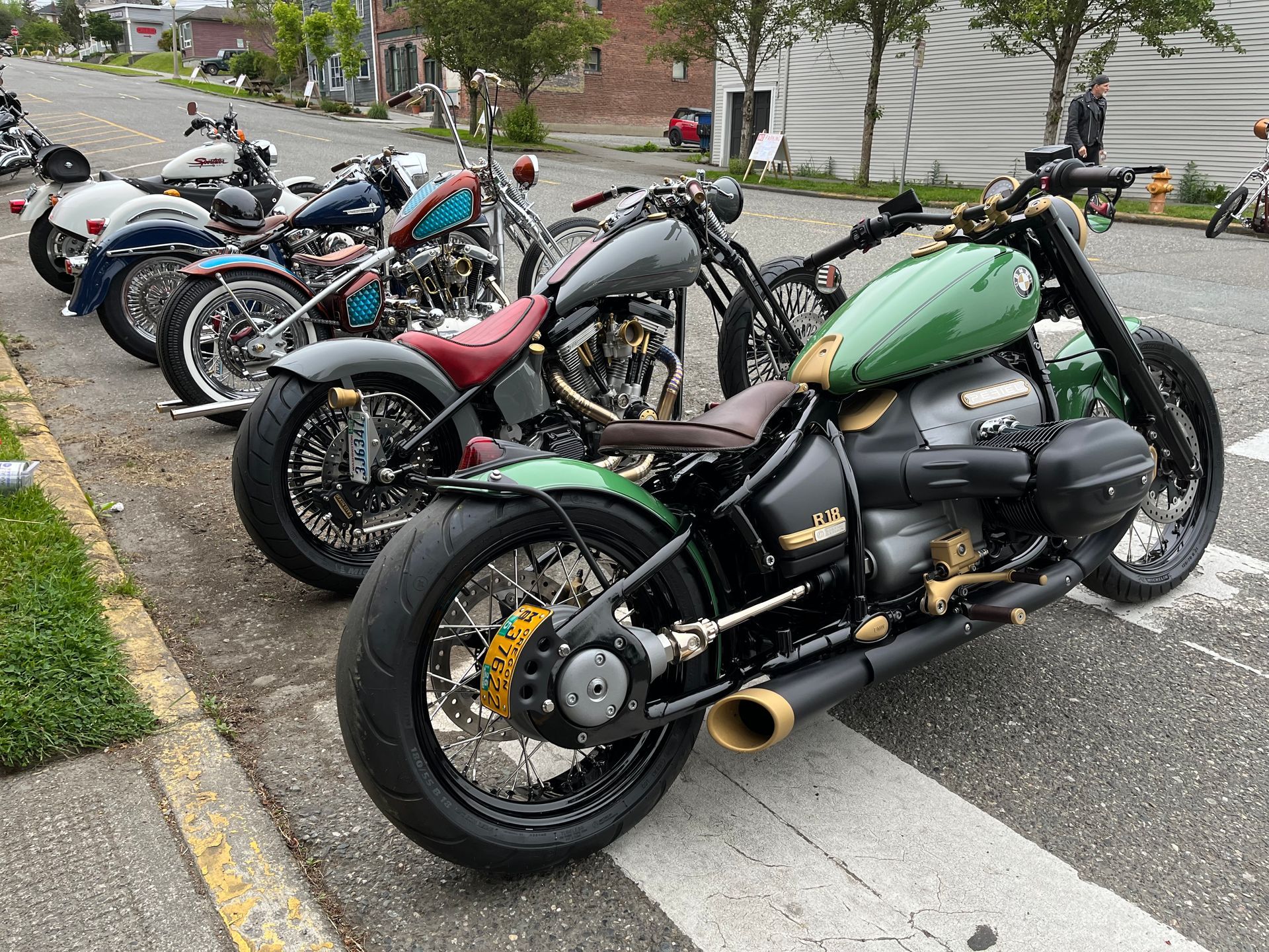 Custom motorcycles parked curbside on a residential street, including a green and black bike in the foreground.