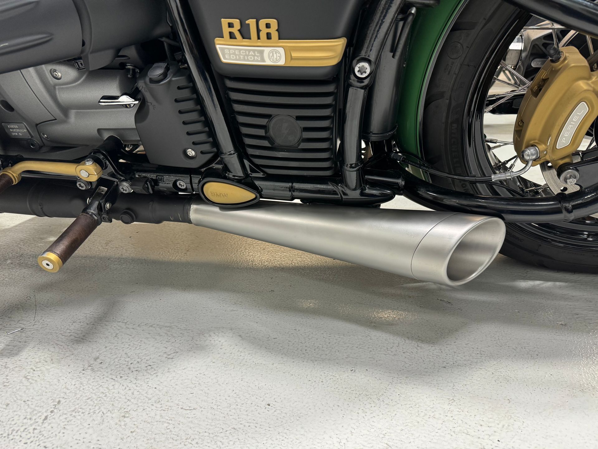 Black-and-gold motorcycle engine with a silver exhaust pipe in a garage