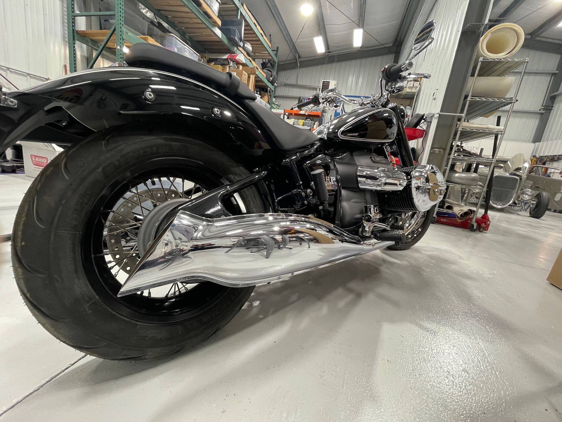 Low-angle view of a custom black motorcycle with chrome exhaust in a workshop