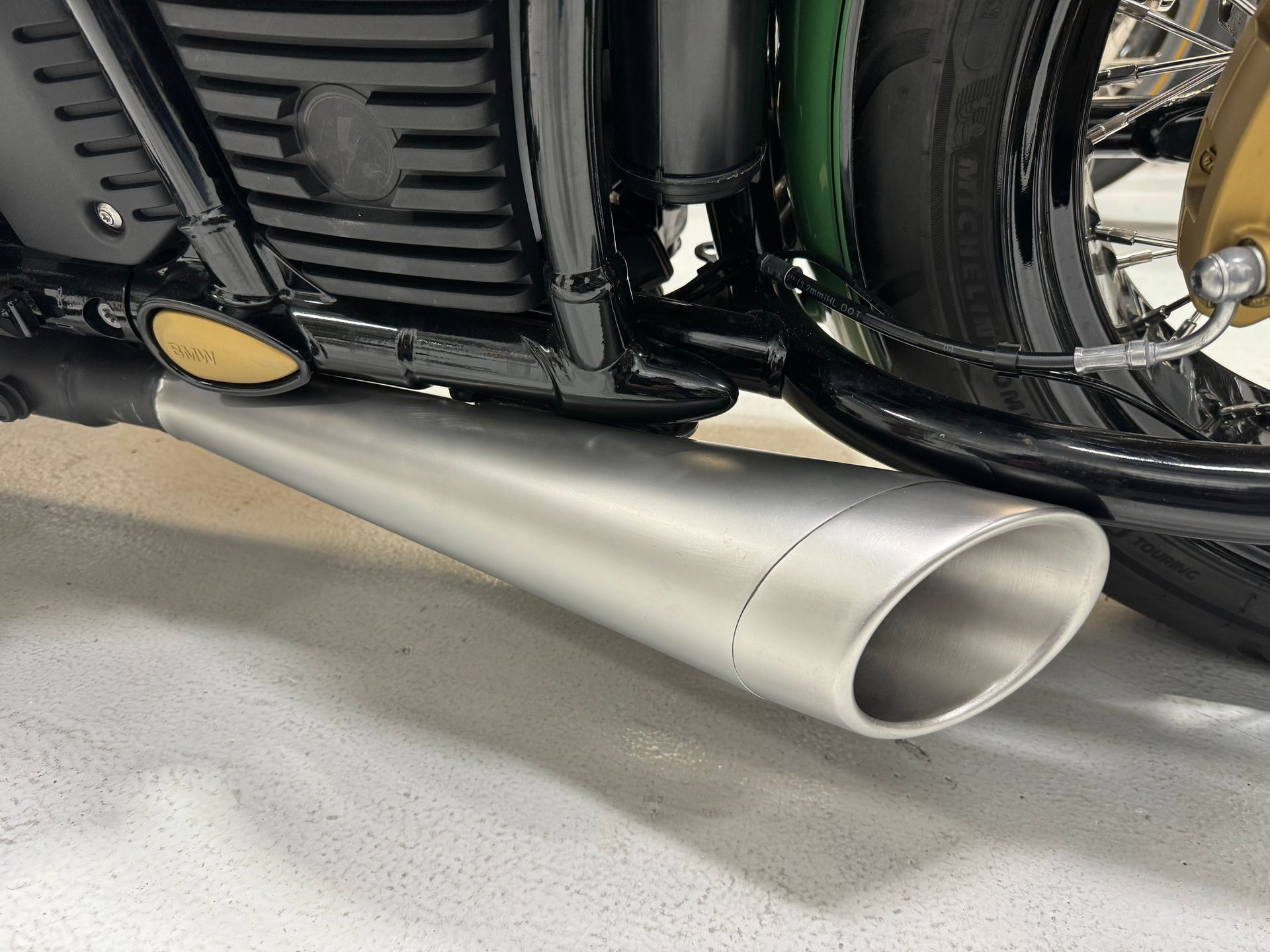 Chrome motorcycle exhaust pipe under a black bike, low side view