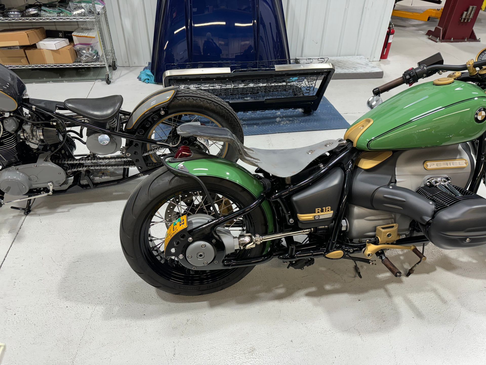 Two custom motorcycles in a garage, including a green bike in the foreground.