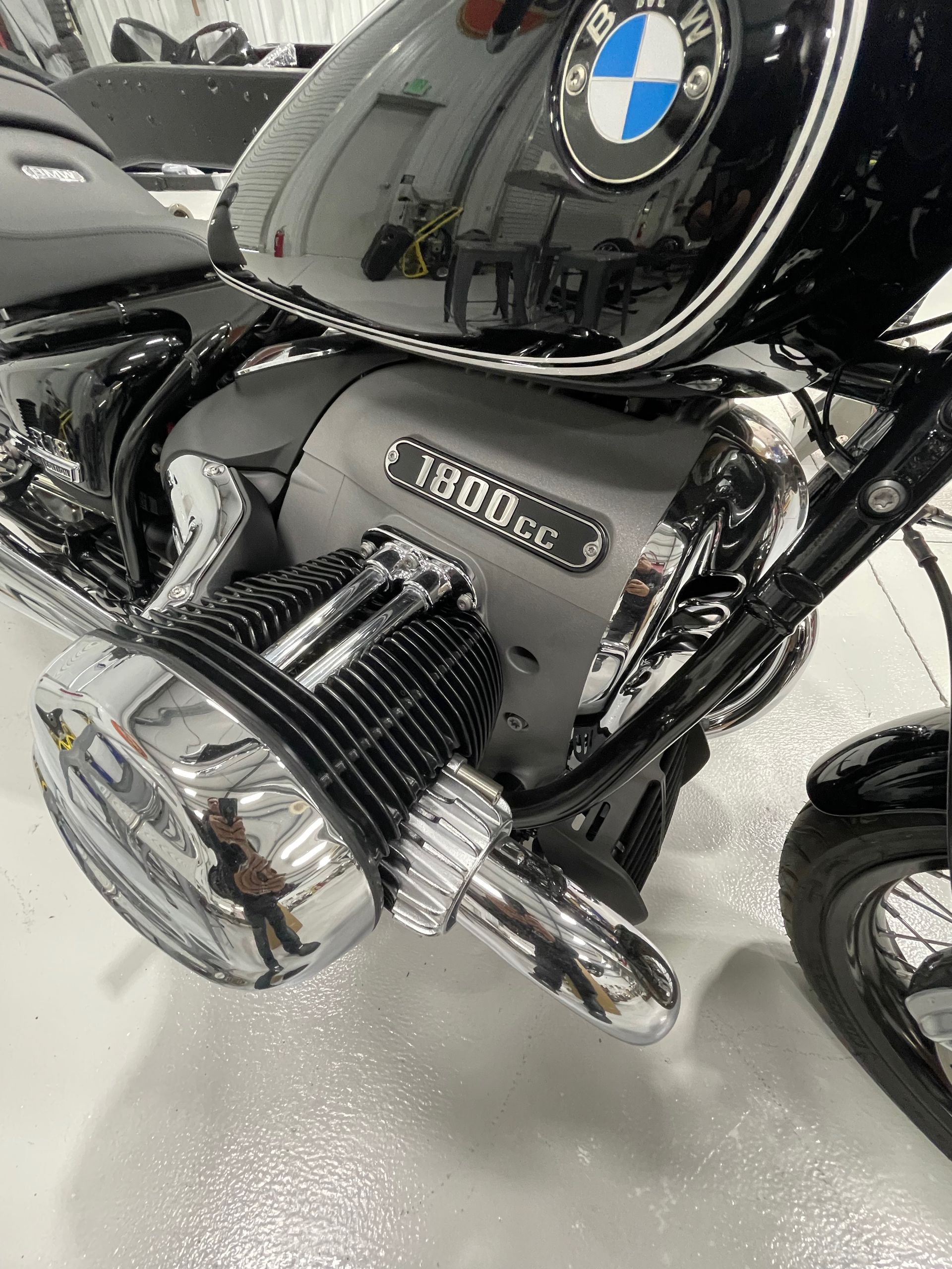 Close-up of a black BMW motorcycle engine and chrome components on a white showroom floor