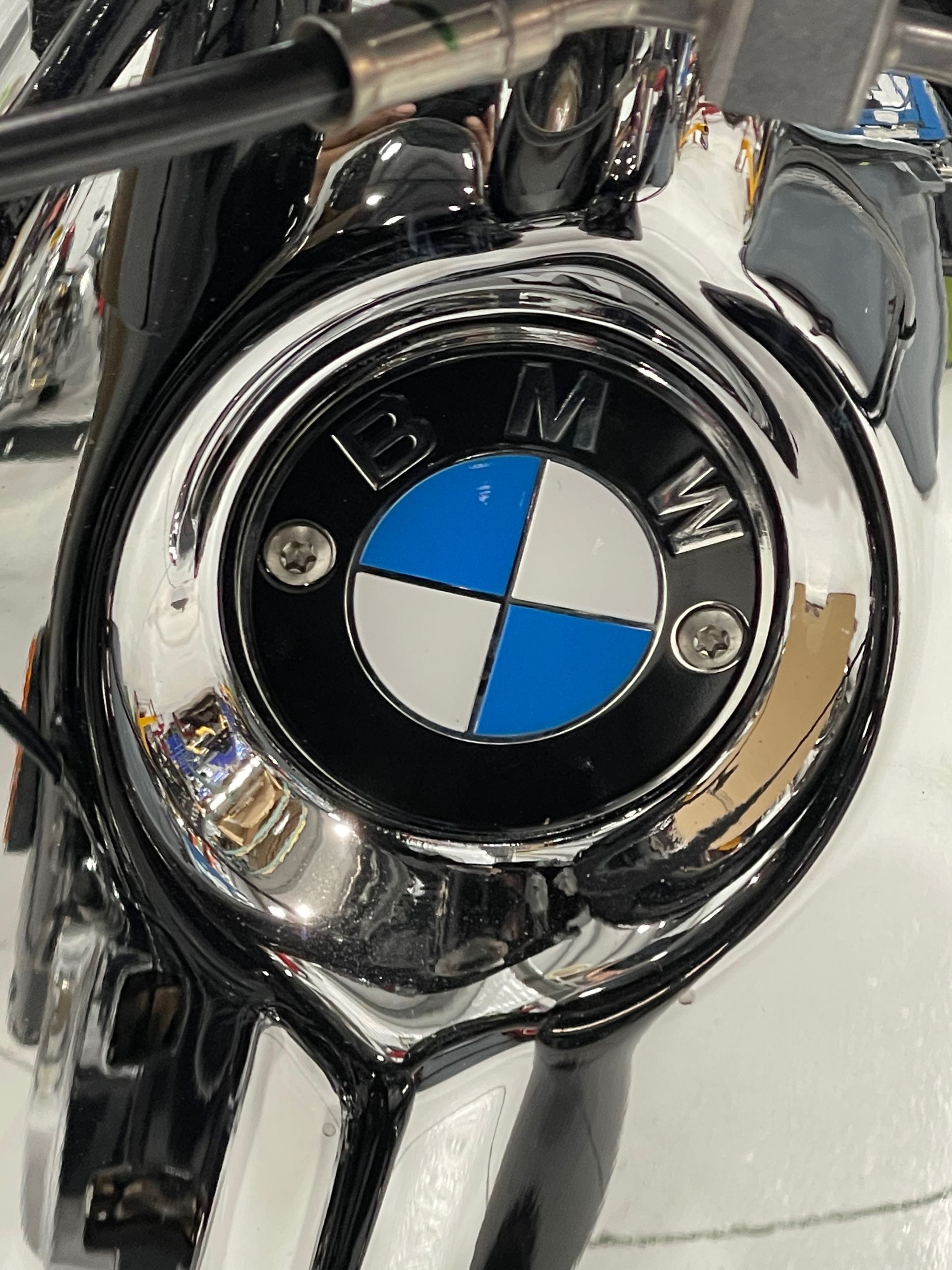 Close-up of a chrome BMW motorcycle emblem with blue, white, and black detailing.