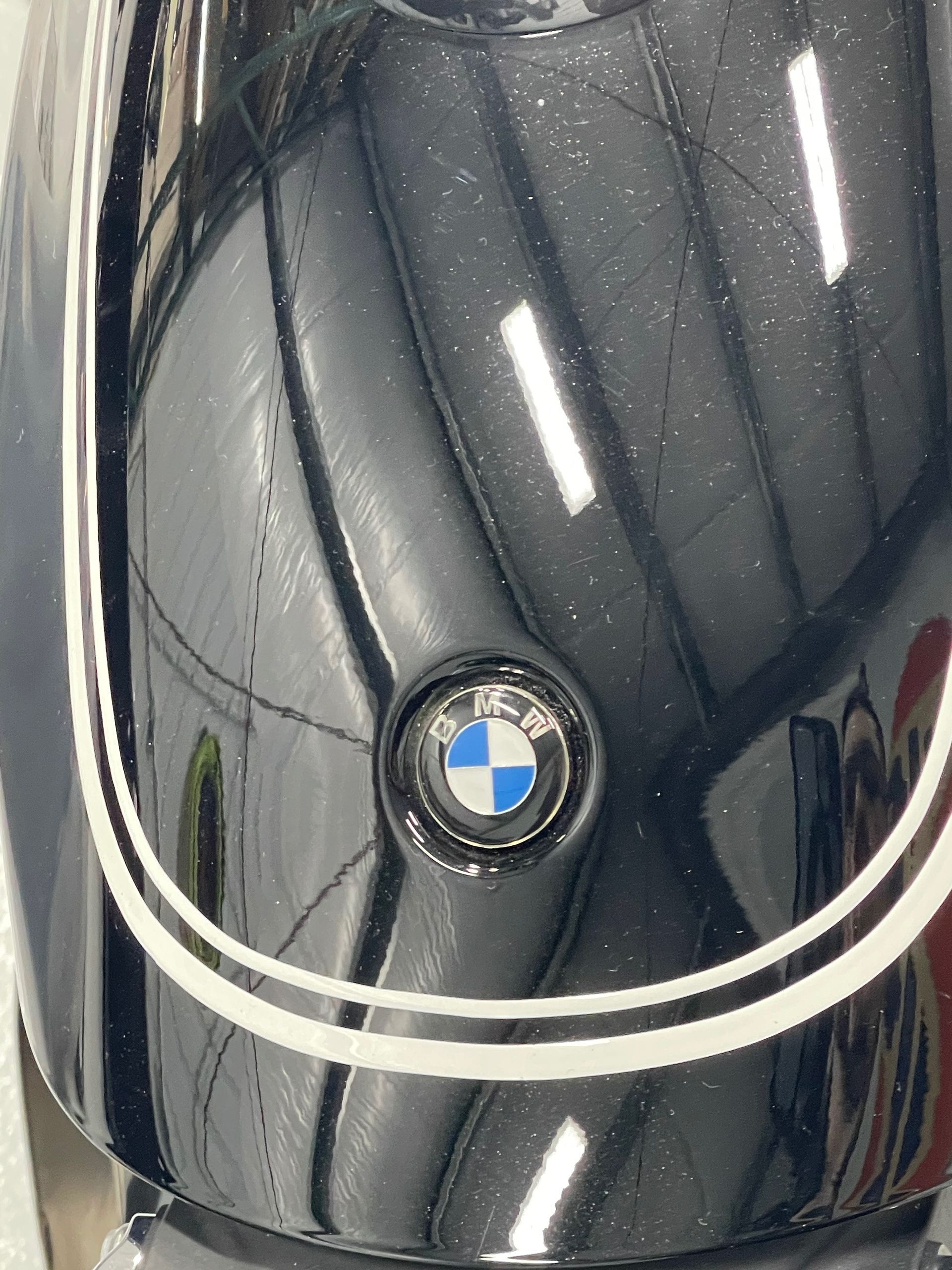 Close-up of a glossy black BMW helmet with the BMW roundel and white stripe accents