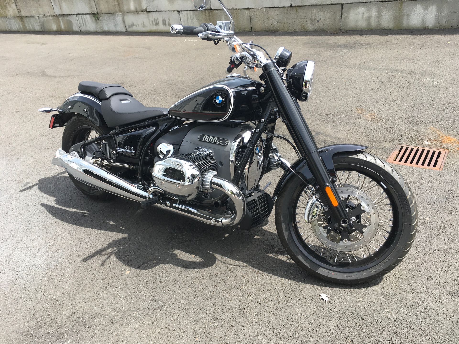 Black cruiser motorcycle parked on pavement beside a concrete wall