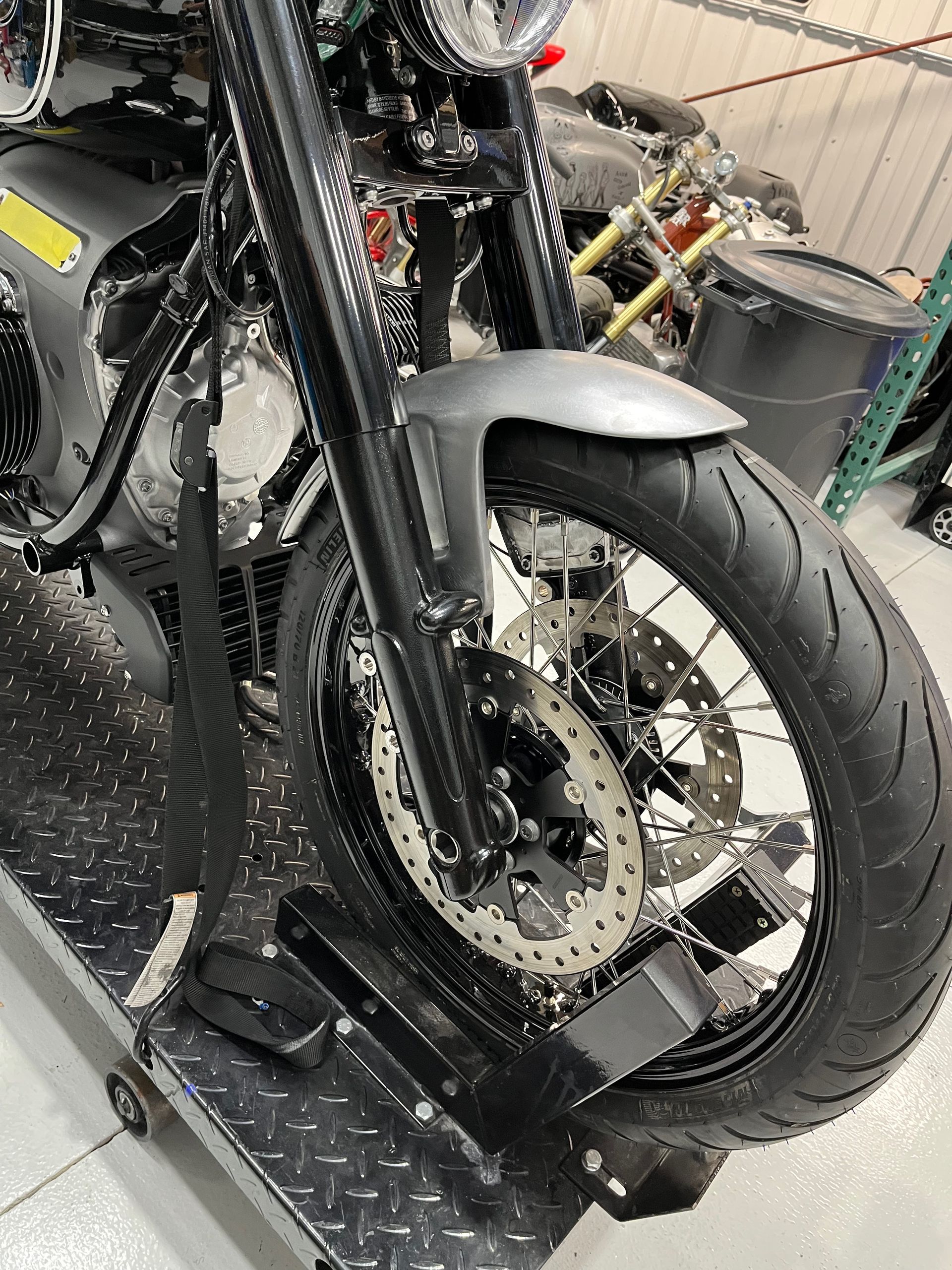 Close-up of a black motorcycle front wheel and fender on a lift in a workshop