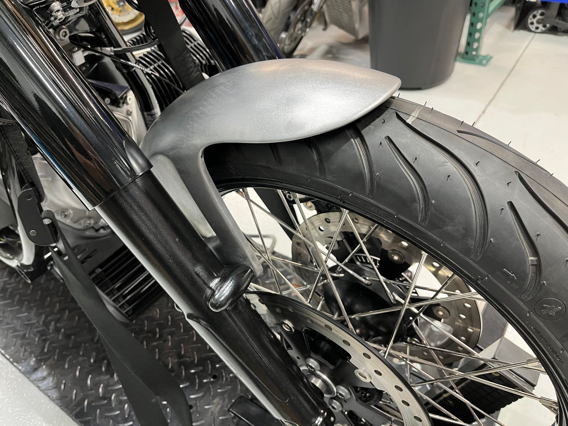 Close-up of a motorcycle's black rear wheel and fender with spoked rim and chrome exhaust.