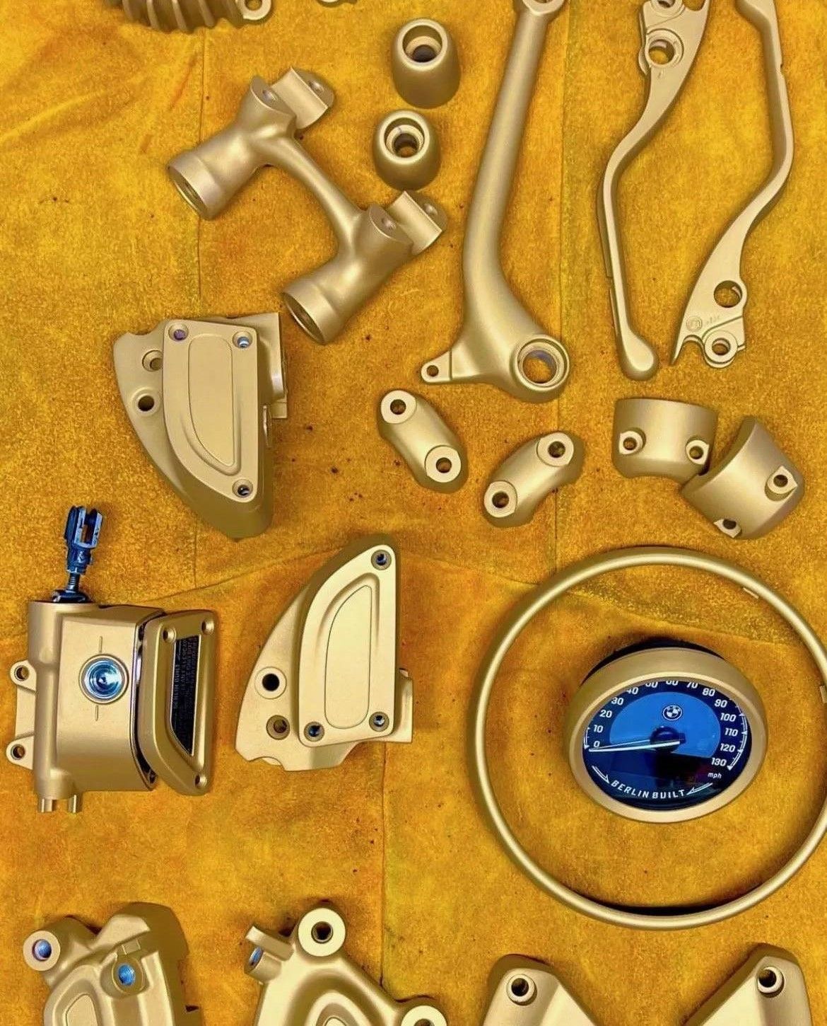 Assorted gold and silver metal hardware and watch parts scattered on a textured golden background