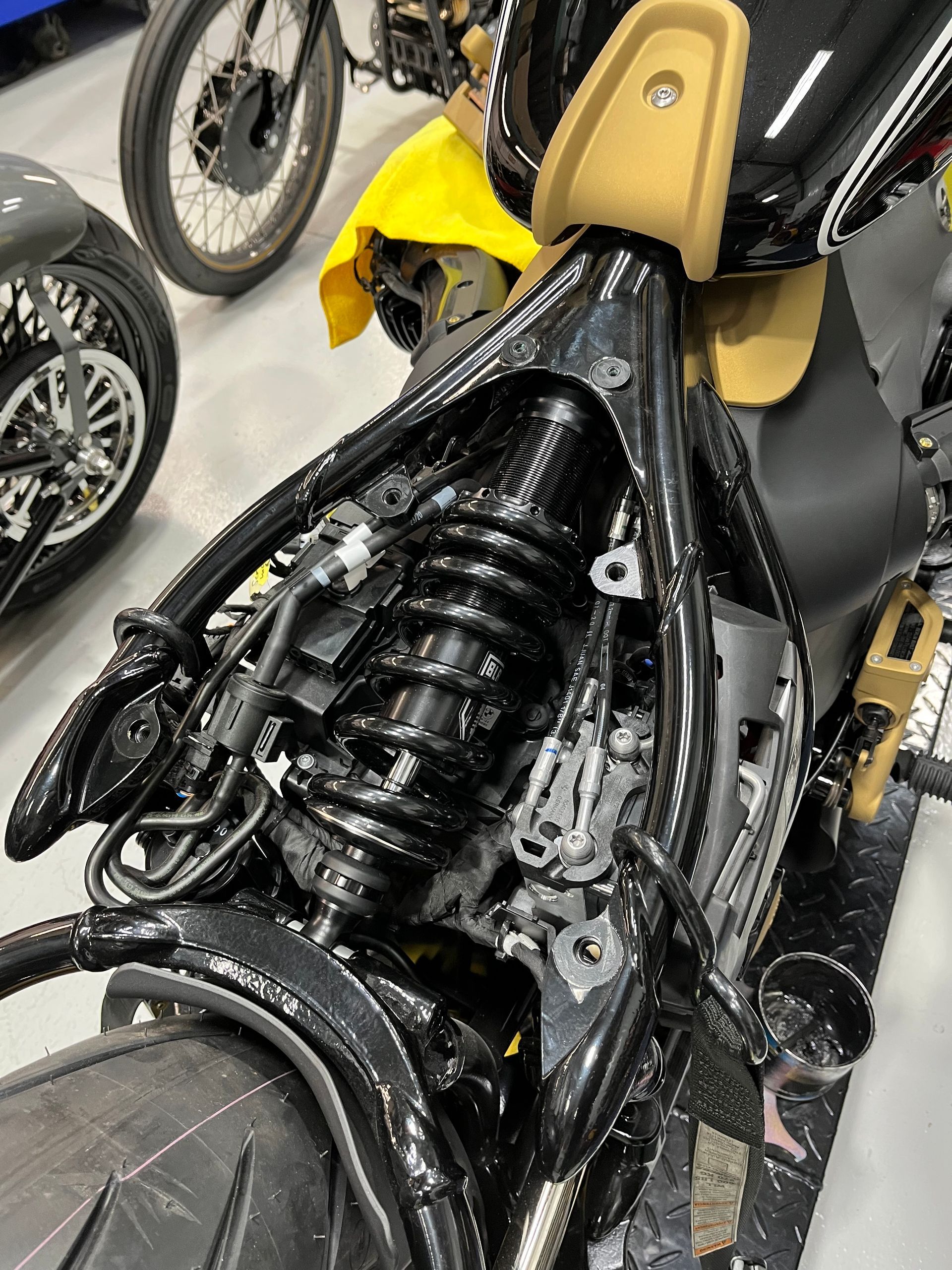 Motorcycle with exposed rear suspension and frame in a workshop setting