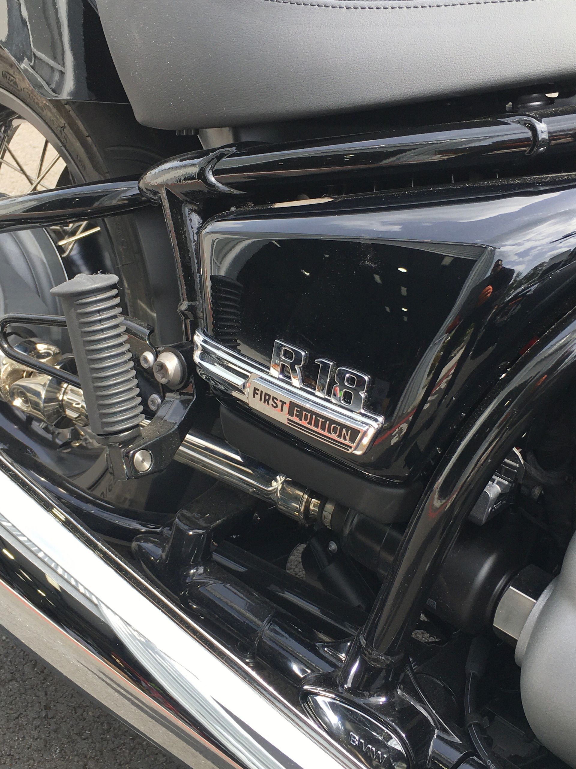 Close-up of a black motorcycle side panel and chrome spring with silver trim badge