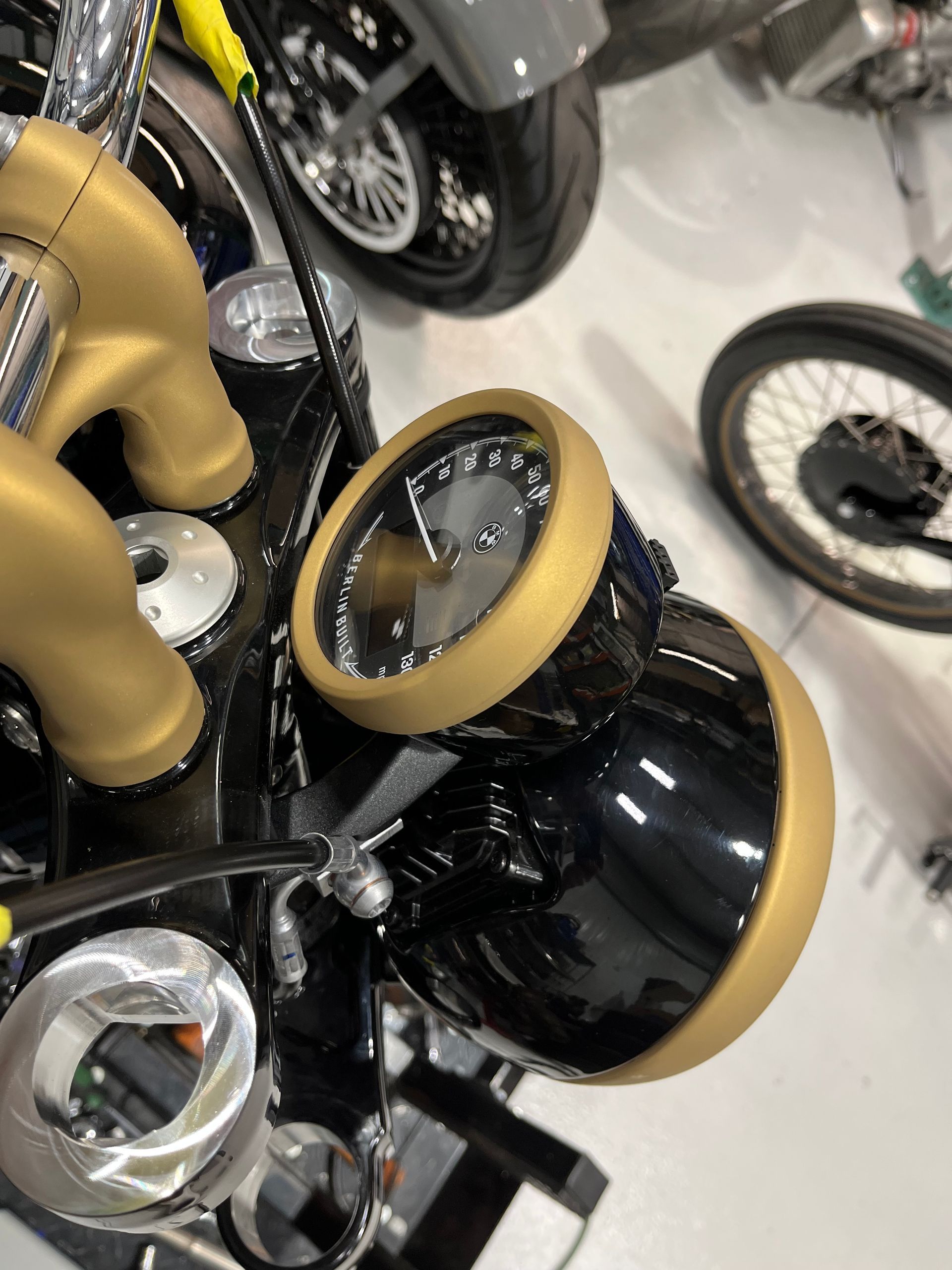 Black motorcycle with tan seat and gold-trimmed headlights in a showroom