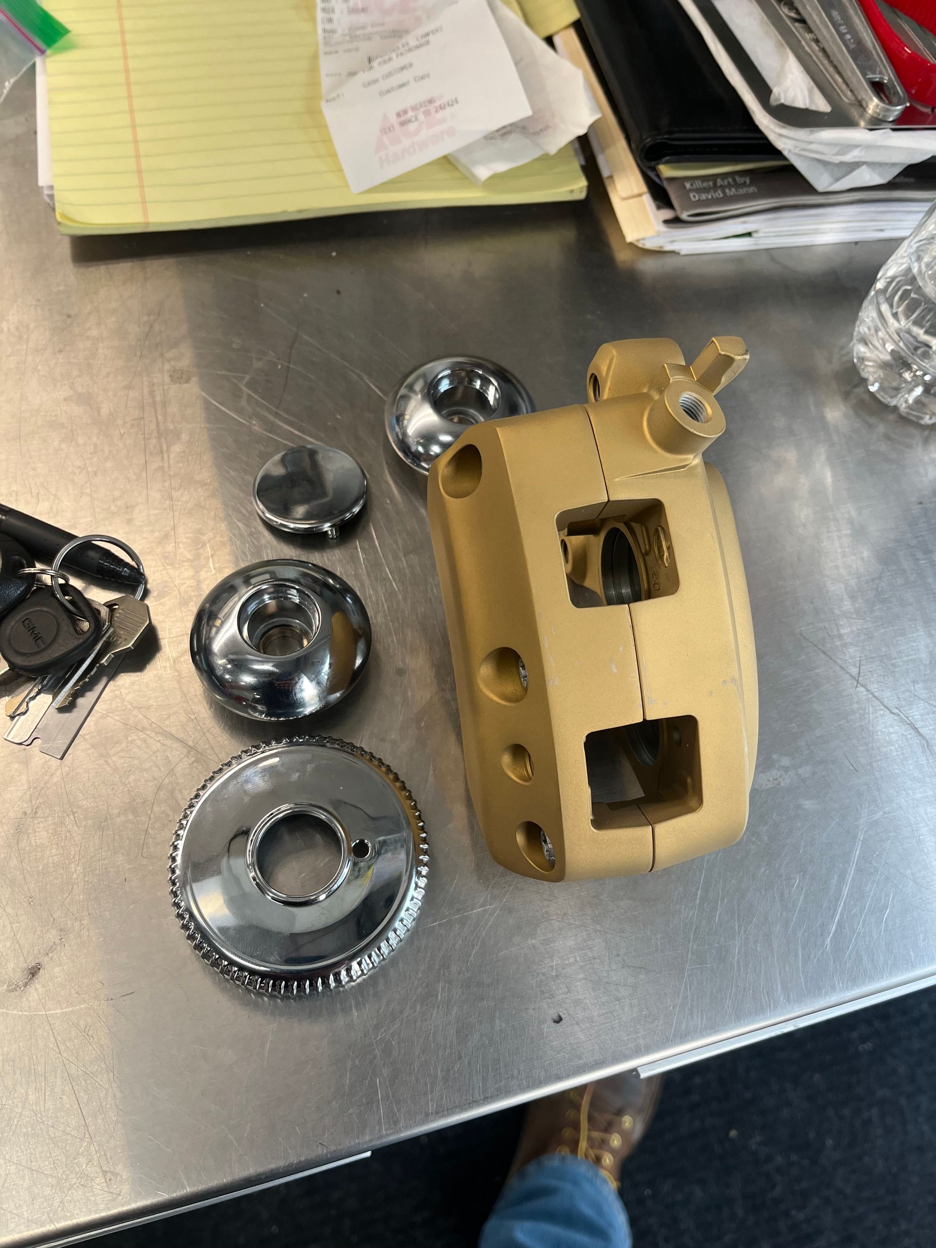 Disassembled silver and gold metal hardware parts on a stainless steel counter