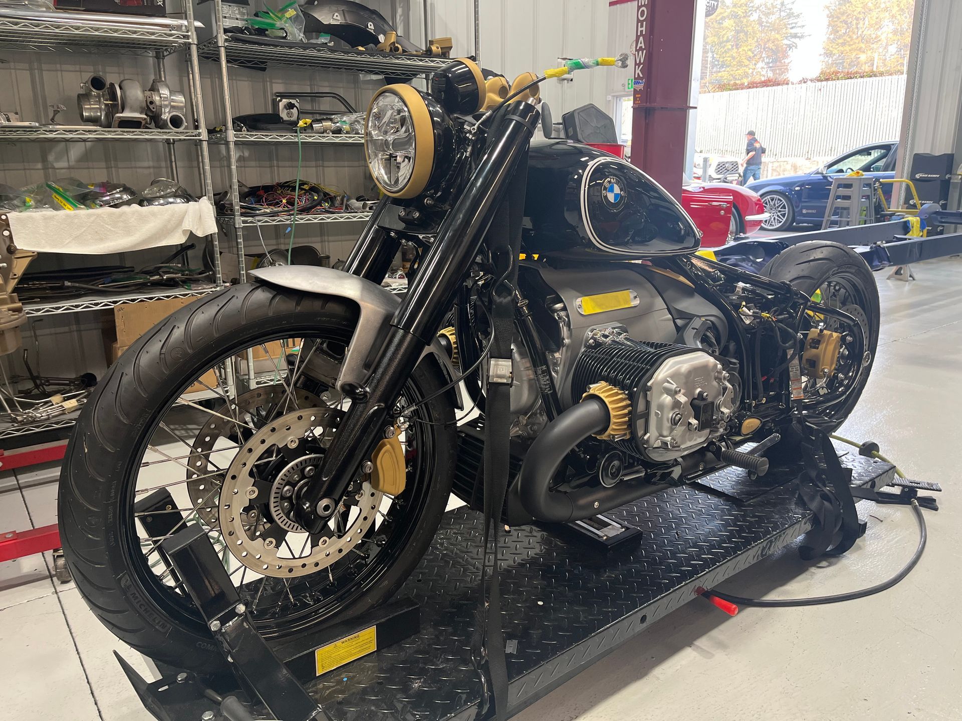 Black custom motorcycle on a lift in a workshop, with tools and shelves in the background