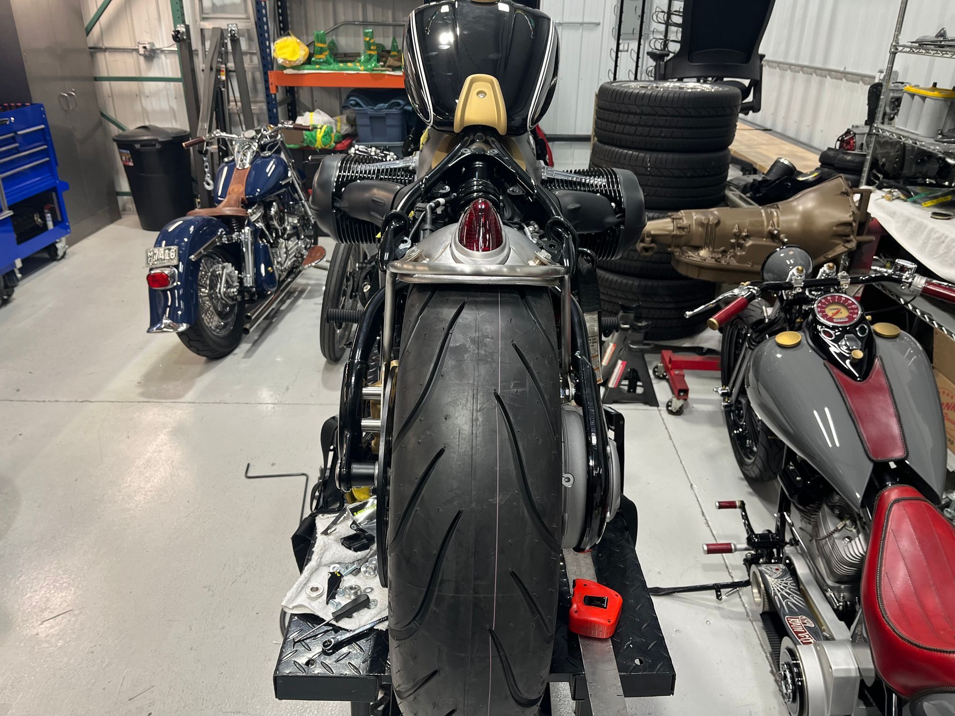 Rear view of a black sport motorcycle in a workshop, flanked by two other bikes.