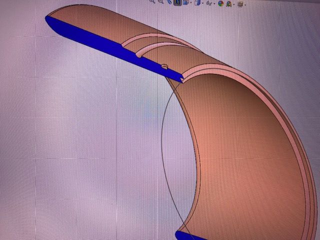 CAD rendering of a curved brown and blue mechanical part on a white background