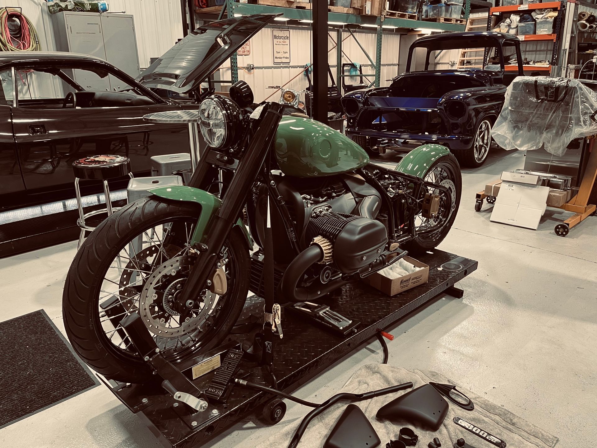 Custom green motorcycle in a workshop with other bikes and tools nearby